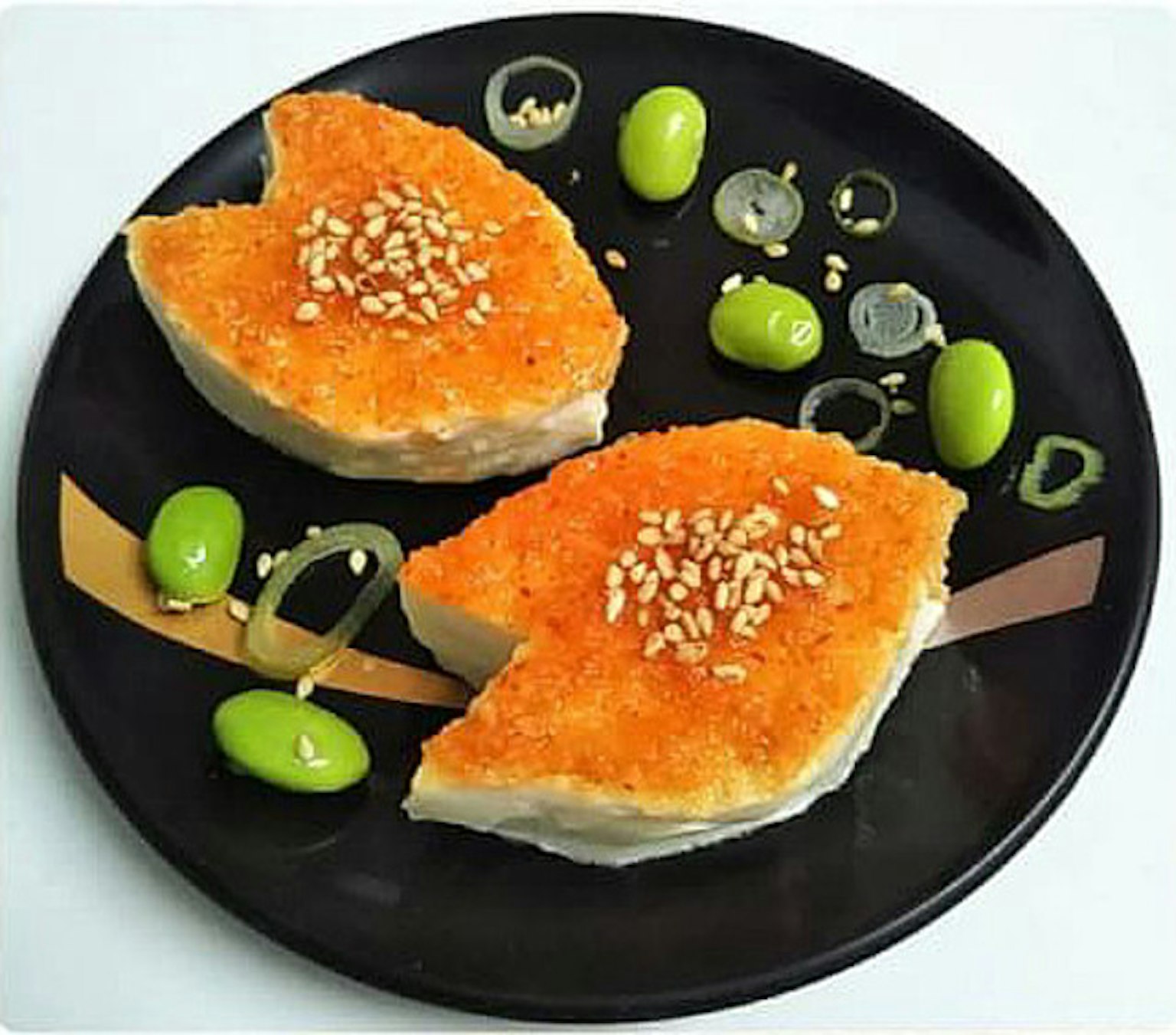 Filets de poisson orange vif servis sur une assiette noire