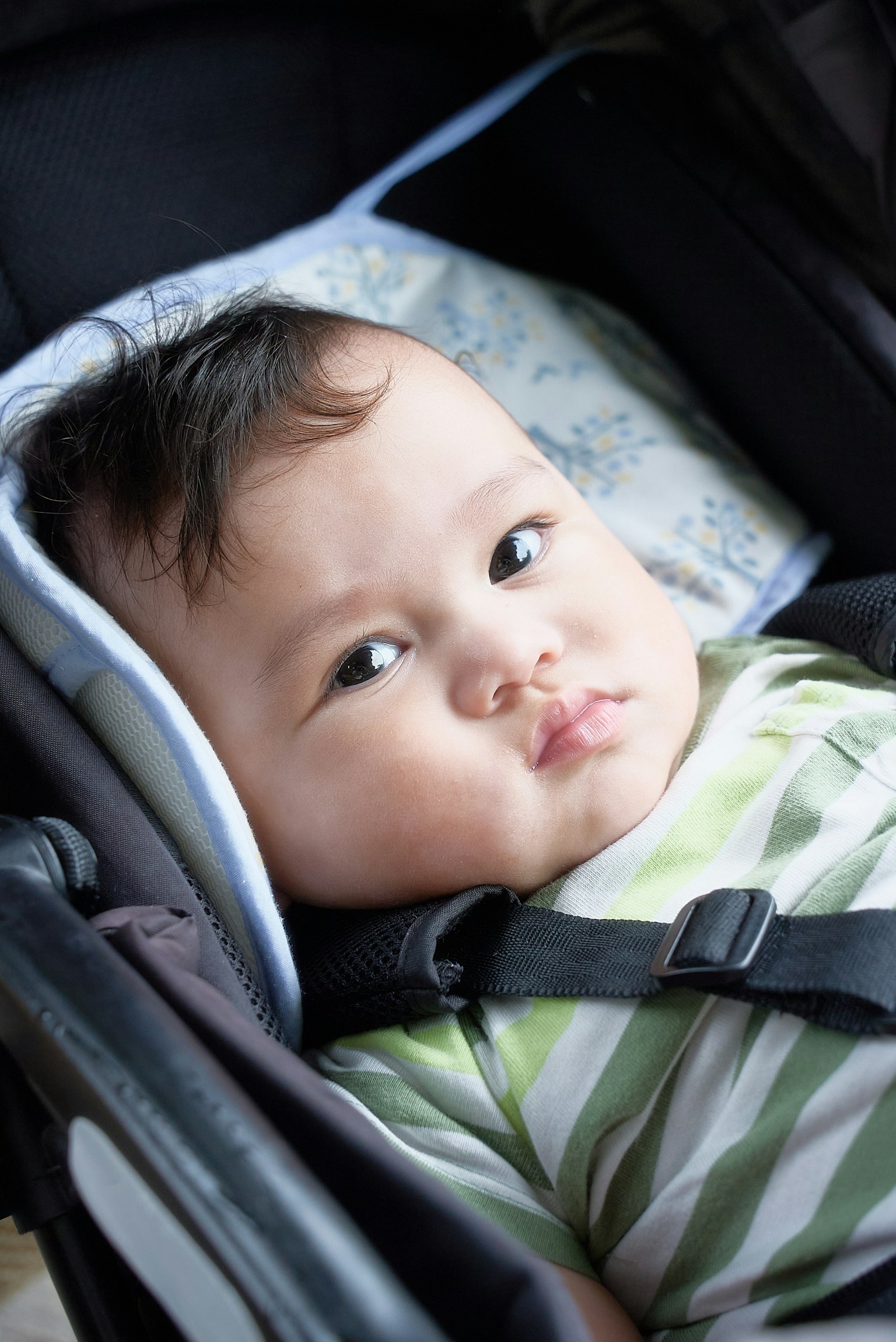 줄무늬 셔츠를 입은 아기가 유모차에 앉아 있다