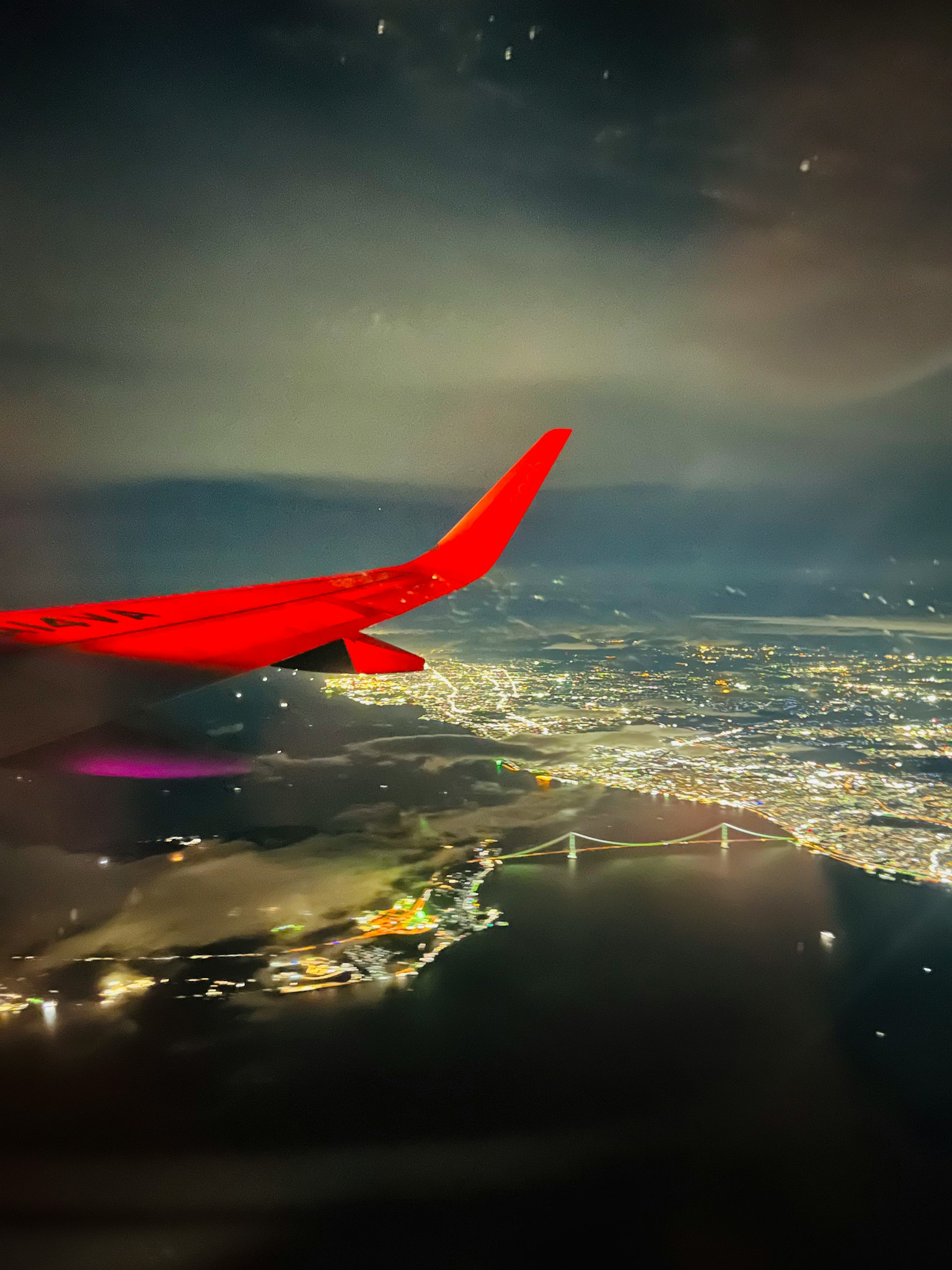 Airplane wing at night overlooking a brightly lit city