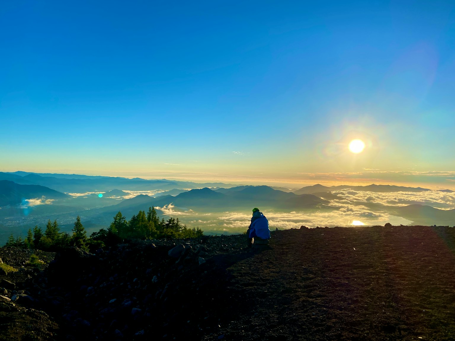 Person, die den Sonnenaufgang über Bergen und Wolkenmeer betrachtet