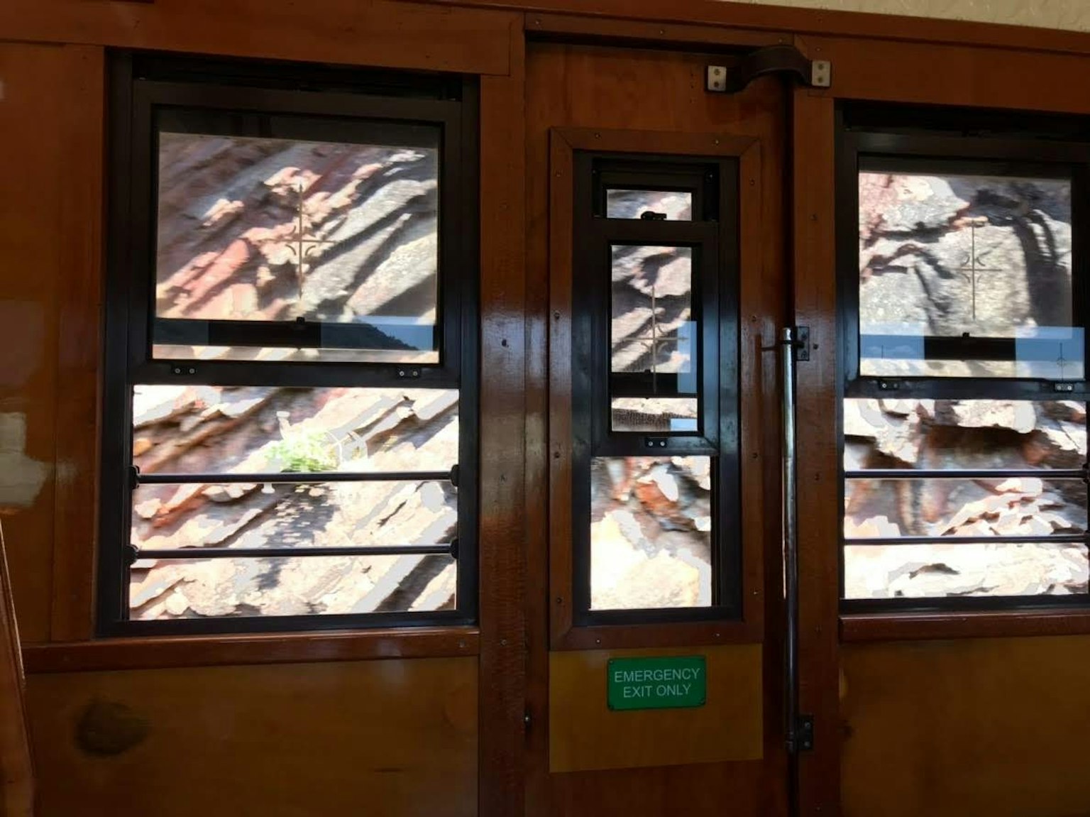 View of rocky landscape through wooden train cabin windows