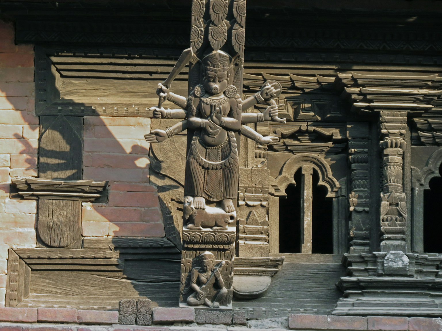 Scultura di una dea con più braccia su un muro di tempio