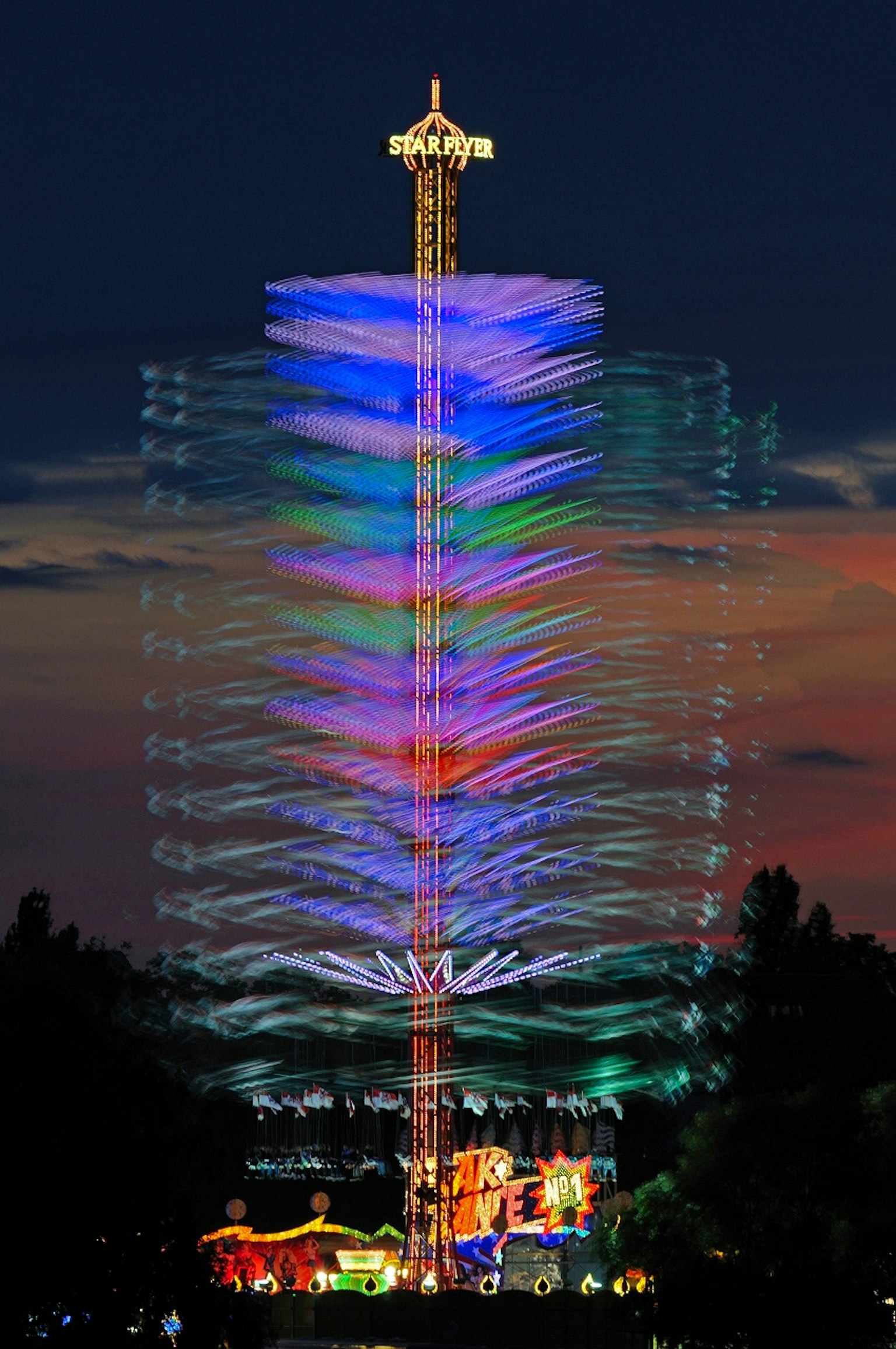 夜空中游乐园塔的彩色光轨迹