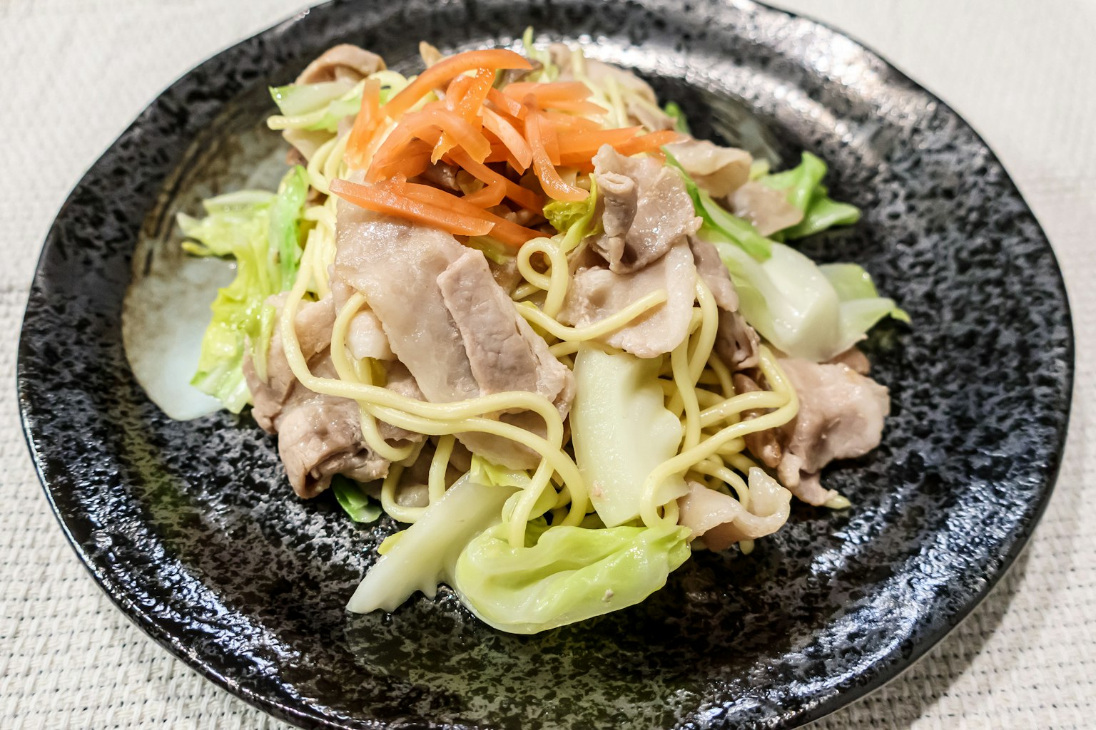 黑色盘子里的炒猪肉和蔬菜