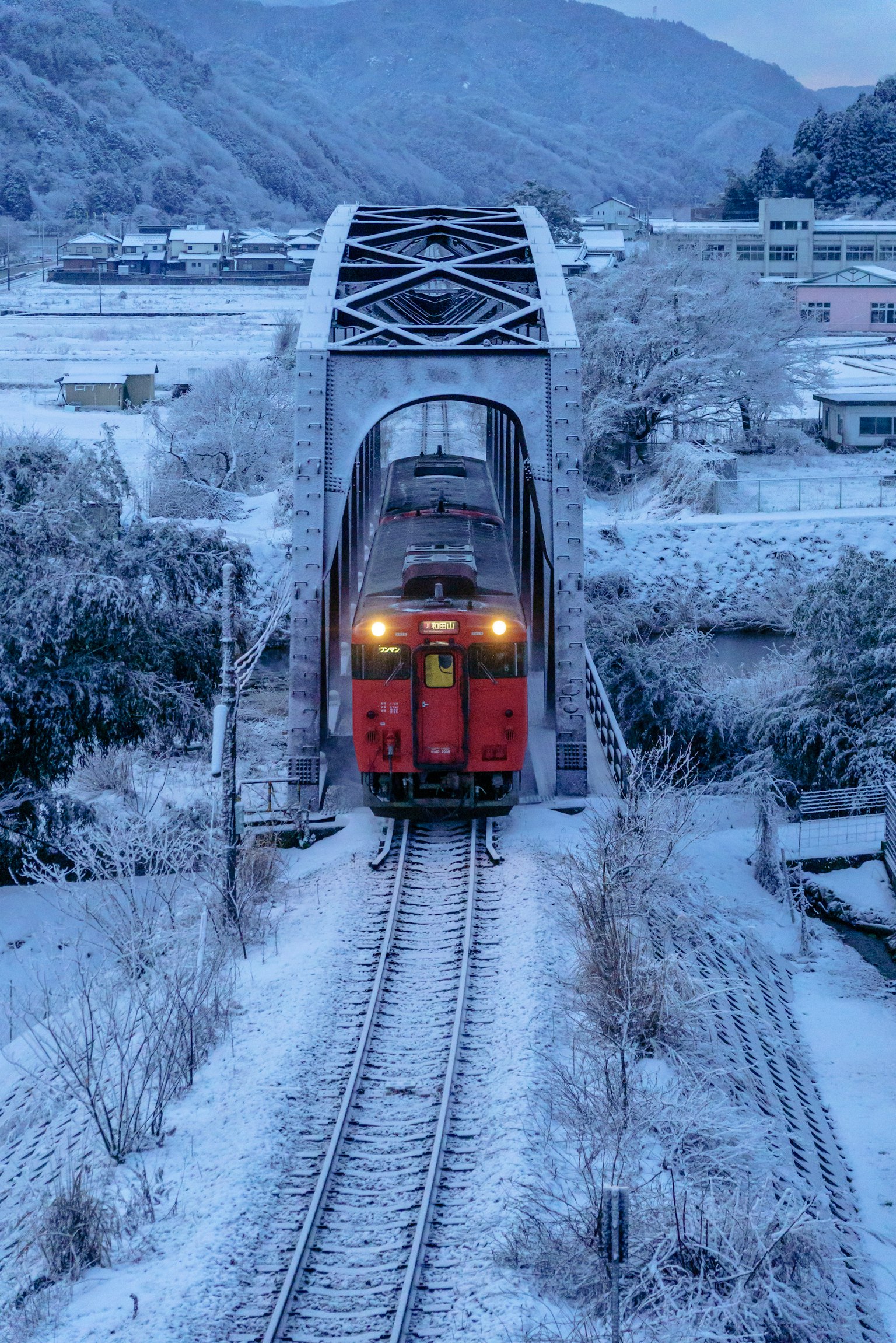 Tren rojo cruzando un puente ferroviario cubierto de nieve