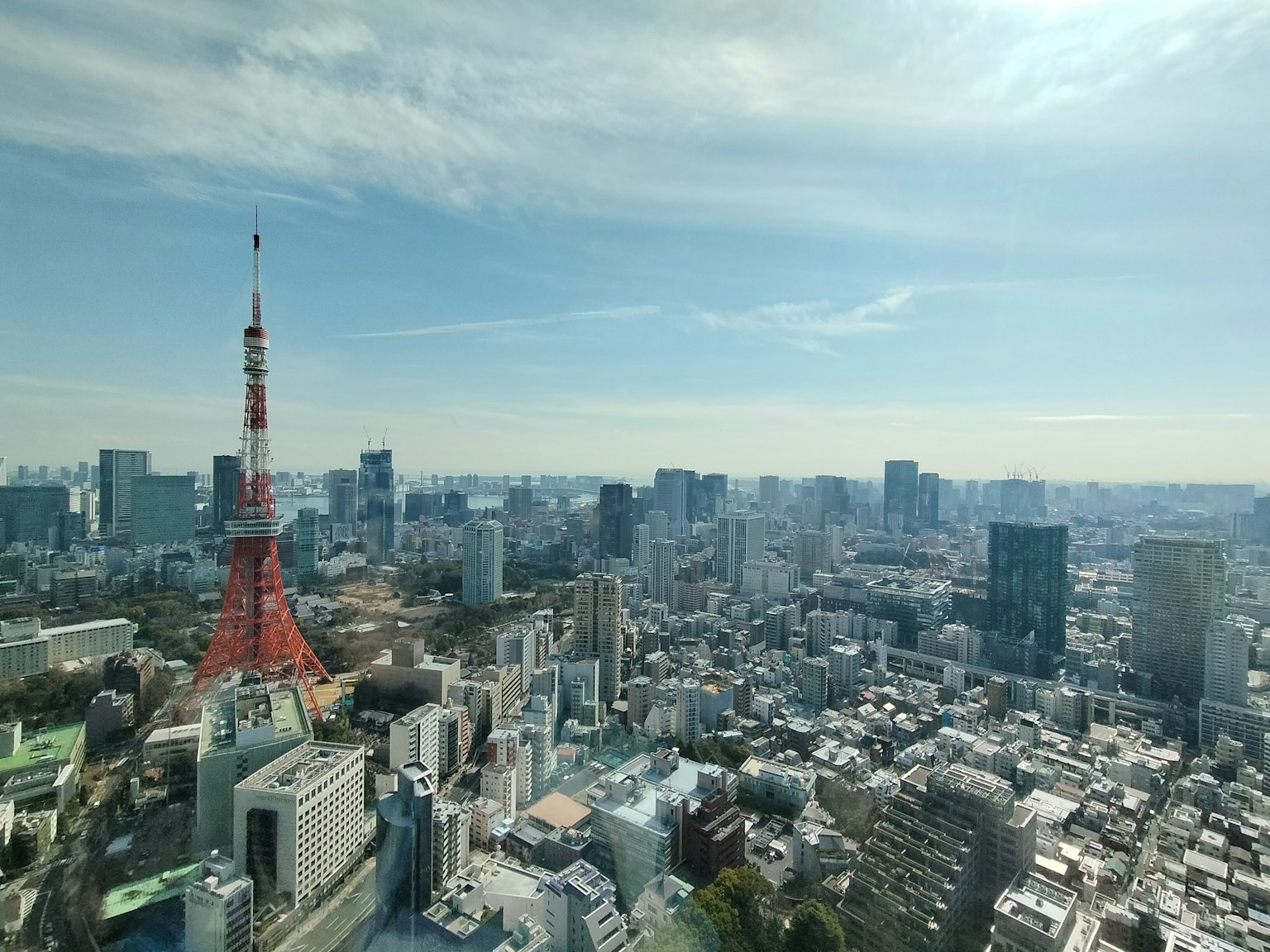 Menara Tokyo dengan lanskap kota yang luas di bawah langit biru dan awan