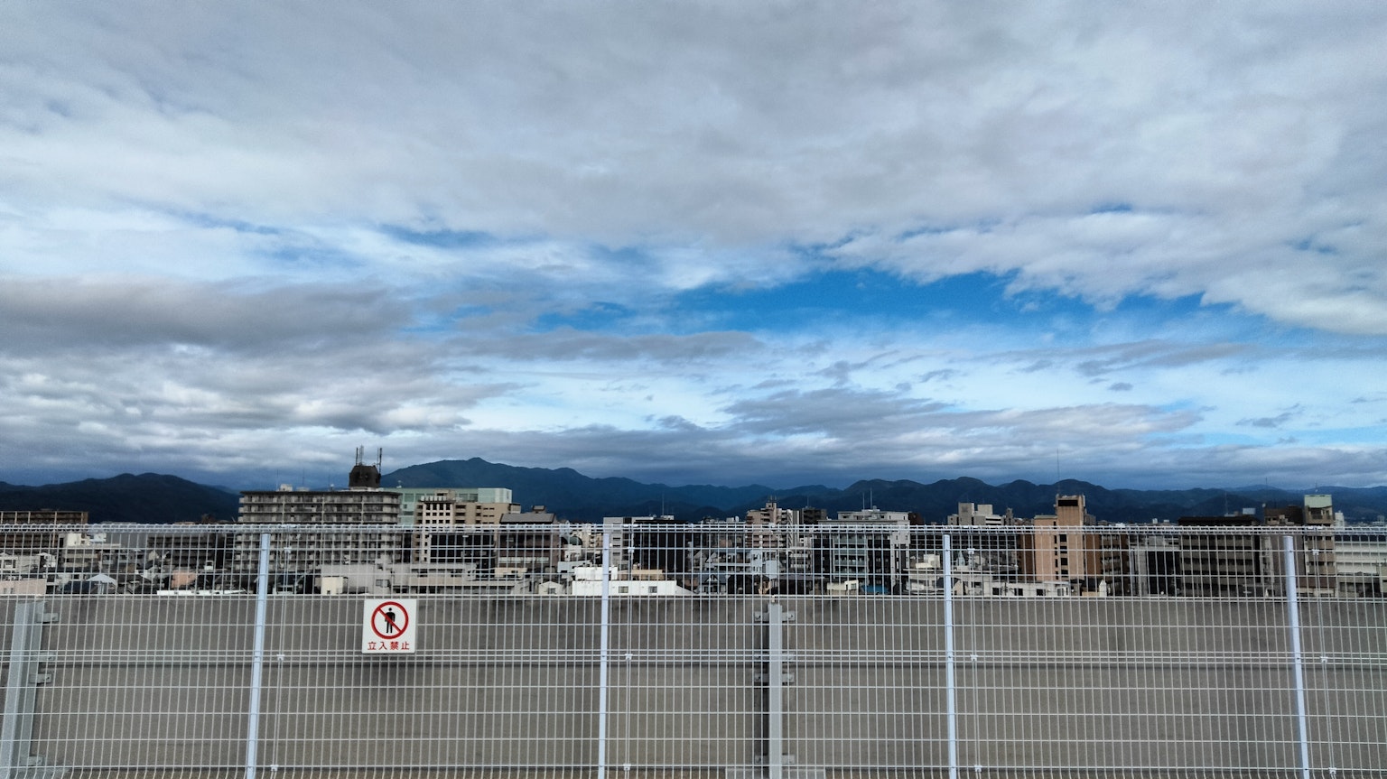 城市风景 蓝天和云彩 前景有围栏 远处有山脉
