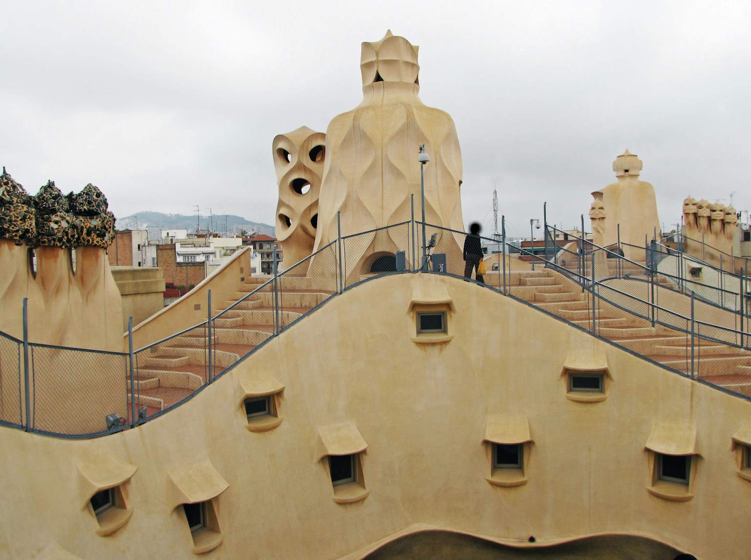 Person standing on the rooftop of Casa Milà with unique chimney sculptures