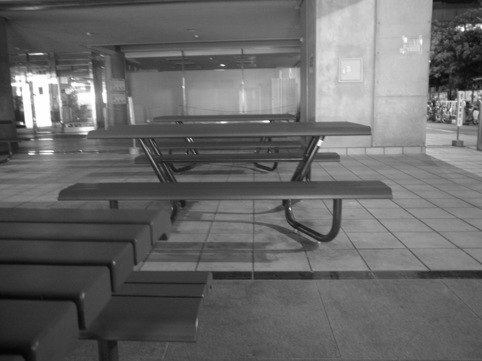 Black and white image of picnic tables arranged in an indoor space