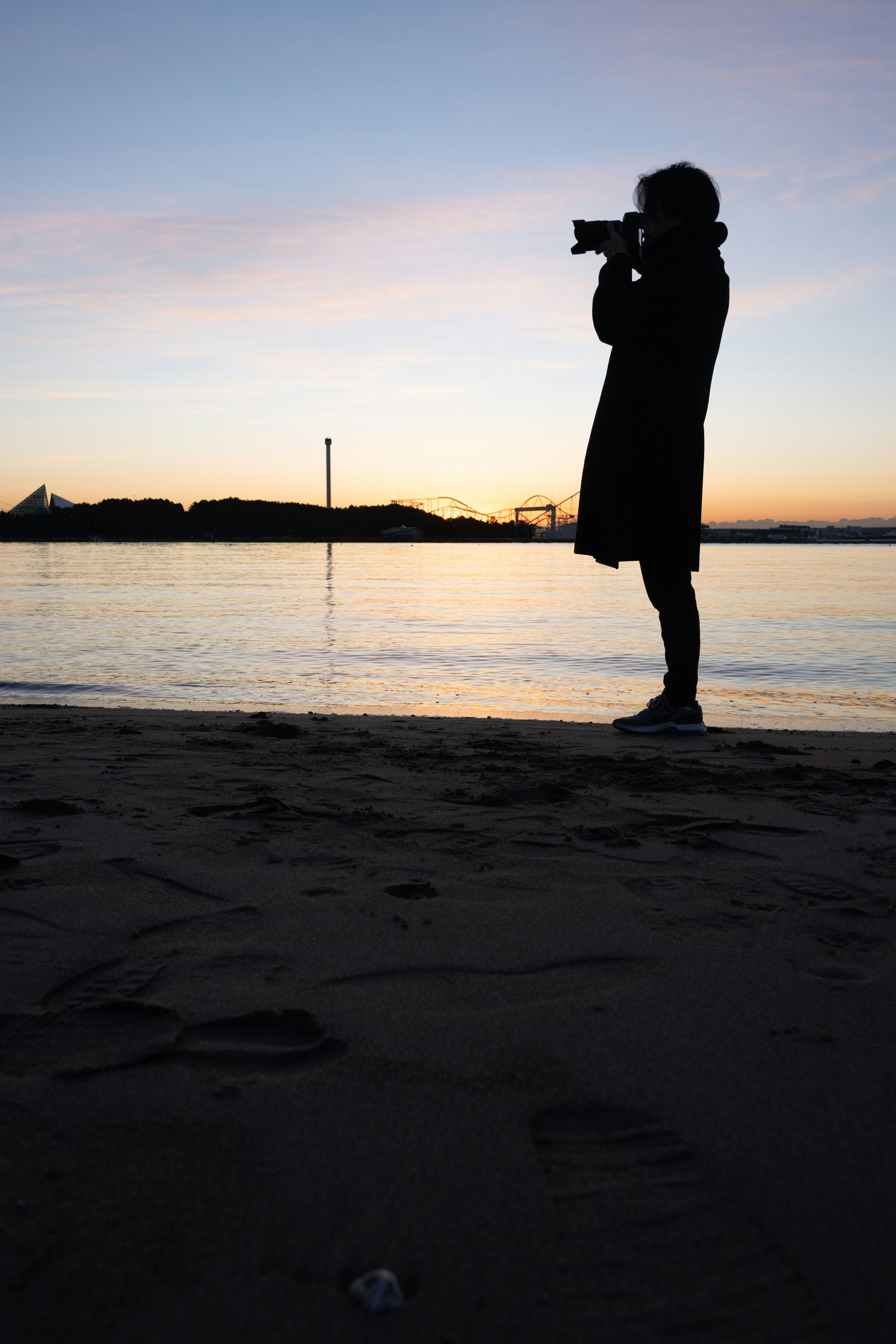 silhouette of a person standing on a seaside at sunset