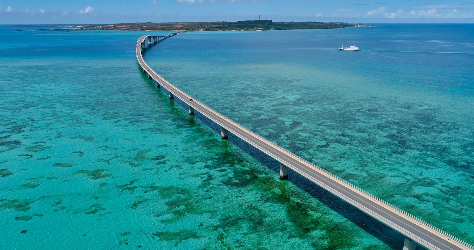 Curved bridge over clear blue waters with coral reefs