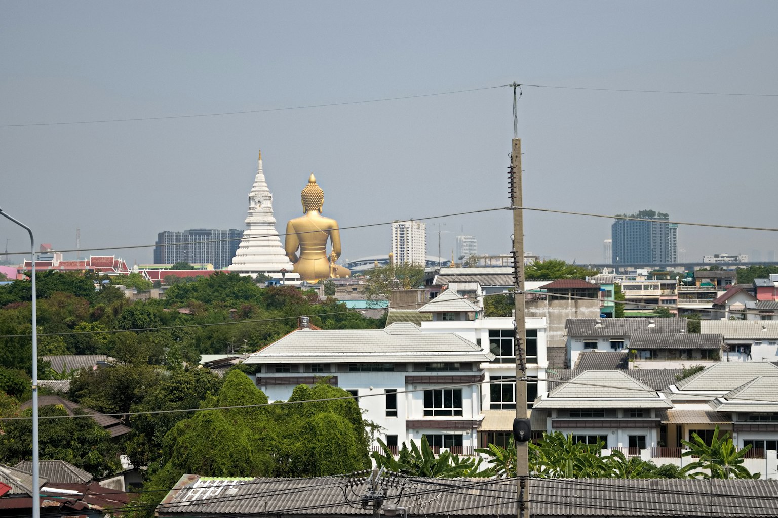 Paisaje urbano con una gran estatua dorada de Buda y una pagoda blanca al fondo