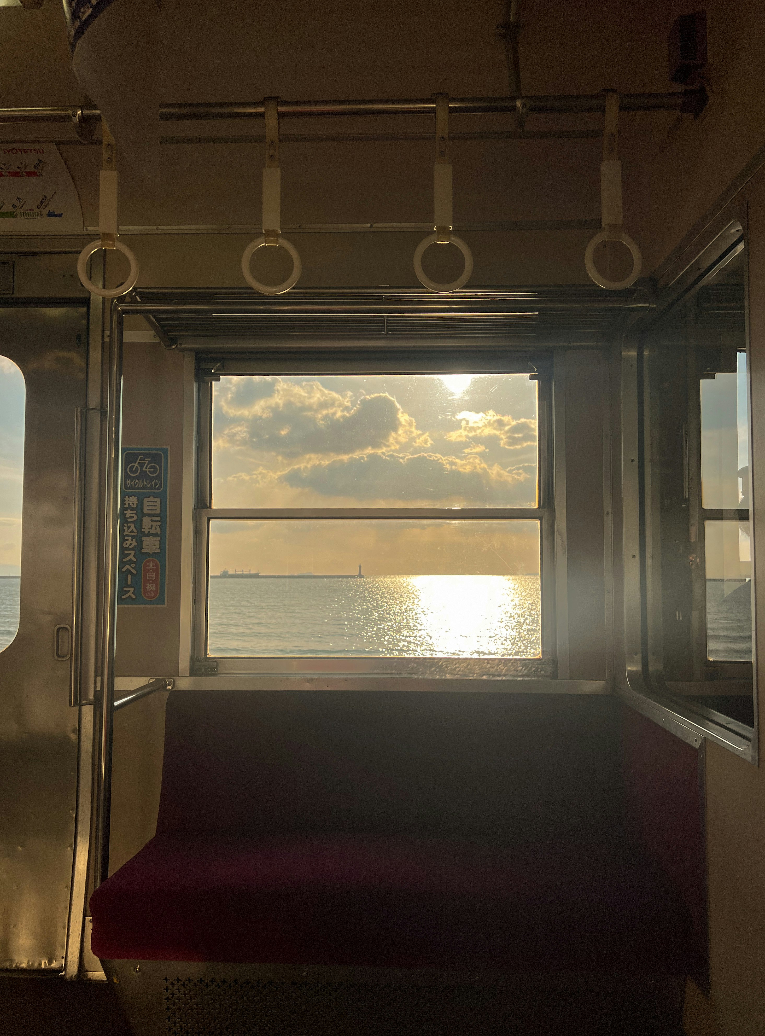 海を望む車窓のベンチ席と夕暮れの光