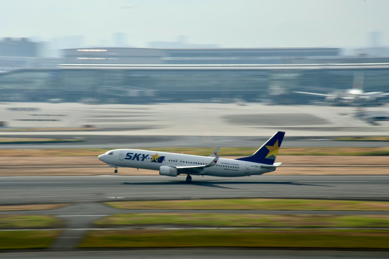 เครื่องบินขึ้นจากรันเวย์พร้อมสนามบินในพื้นหลัง