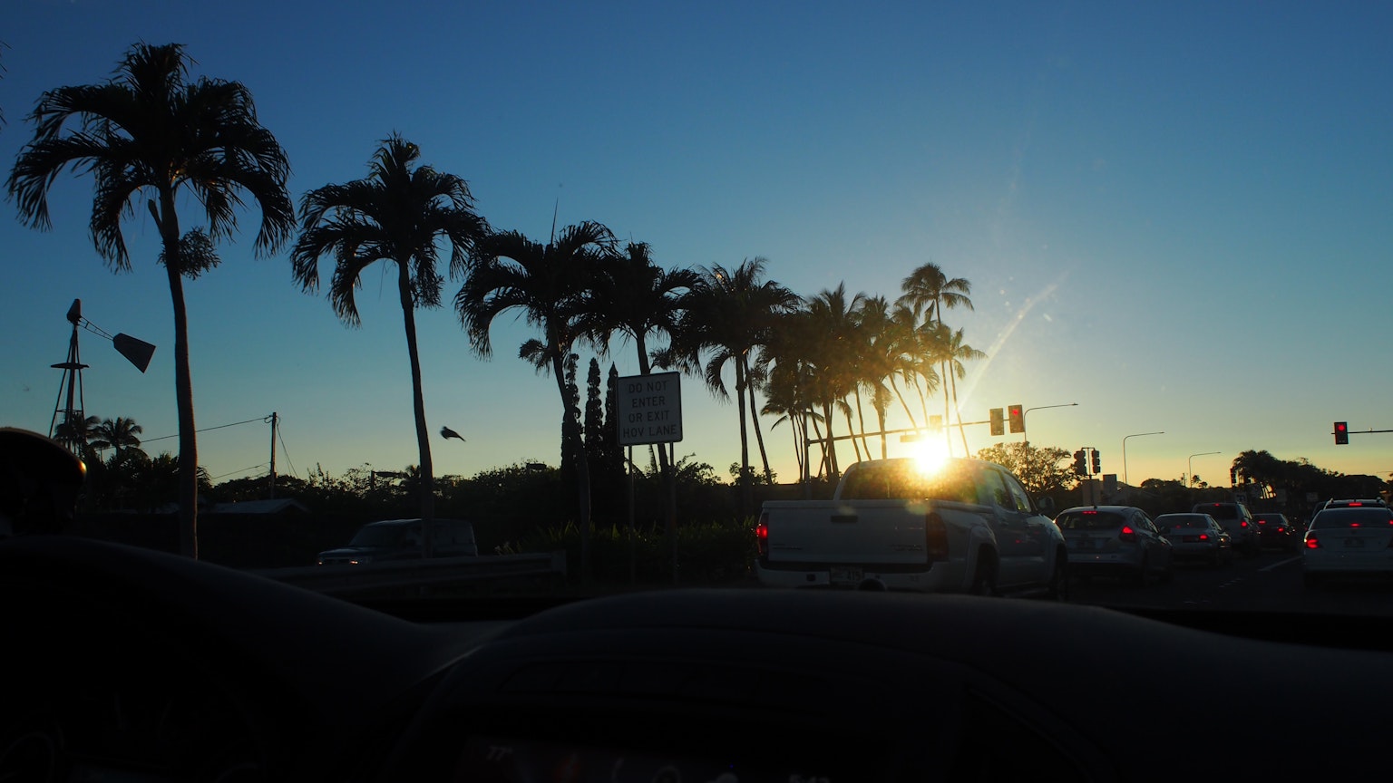 Verkehrsszene mit Palmen im Silhouetten gegen einen Sonnenuntergang