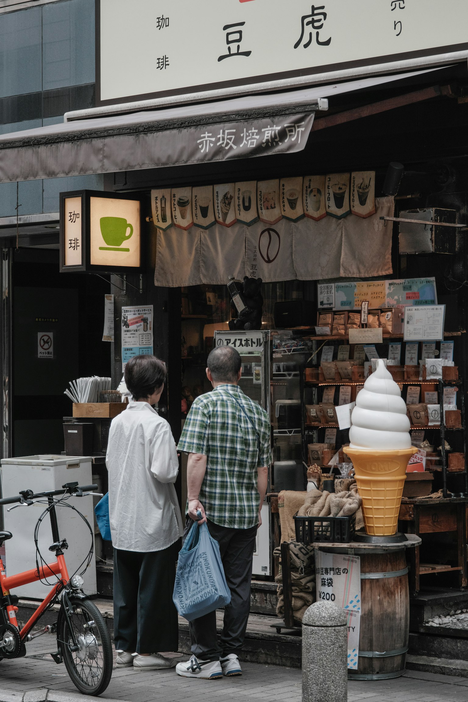 Dua pria berdiri di depan kedai kopi dengan tampilan cone es krim