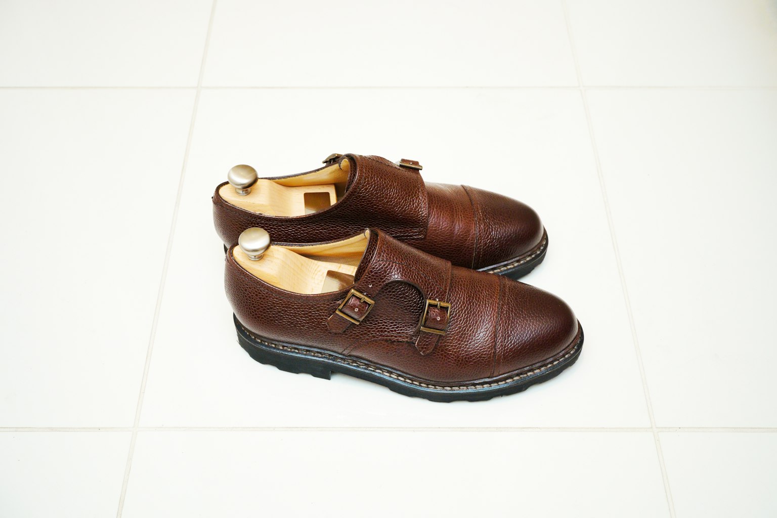 Brown leather shoes positioned on a white floor