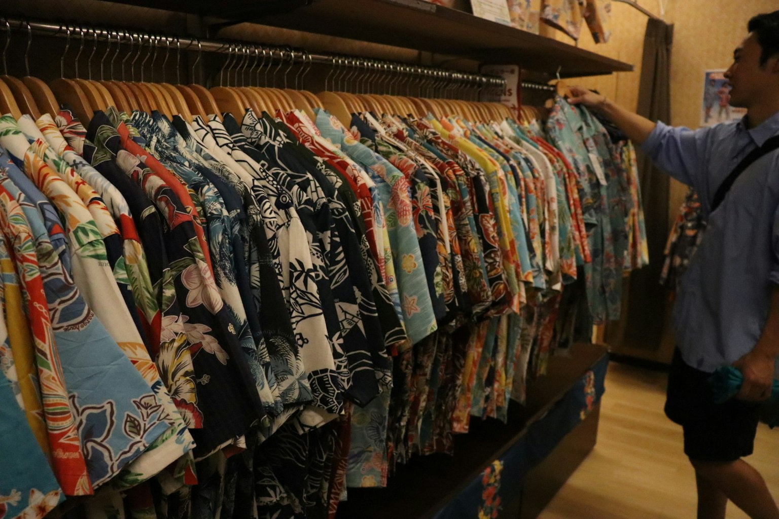 ชายคนหนึ่งเลือกจากการจัดแสดงเสื้ออโลฮ่าสีสันสดใสในร้าน