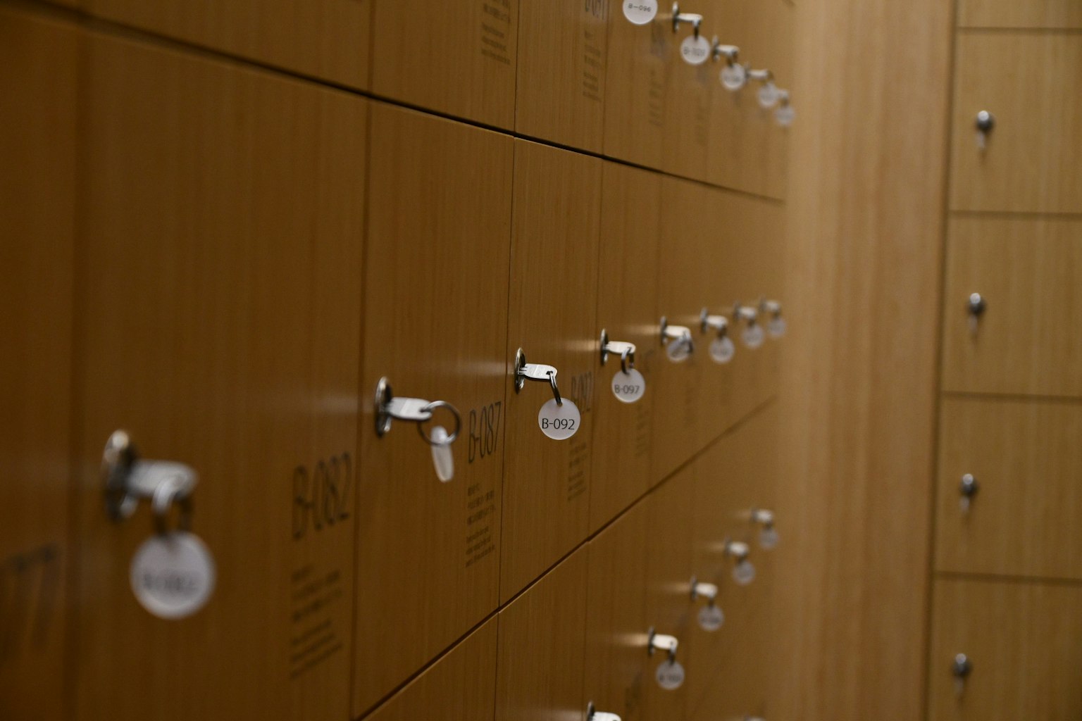 A row of wooden lockers with locked compartments and keys