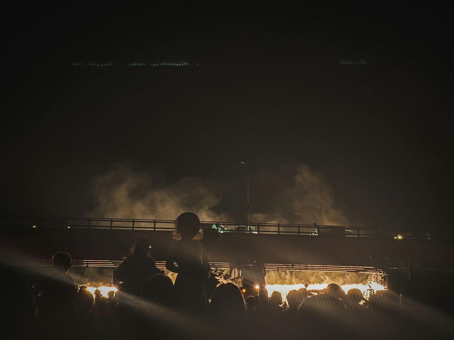 Silhouette d'une foule contre de la fumée et des flammes la nuit