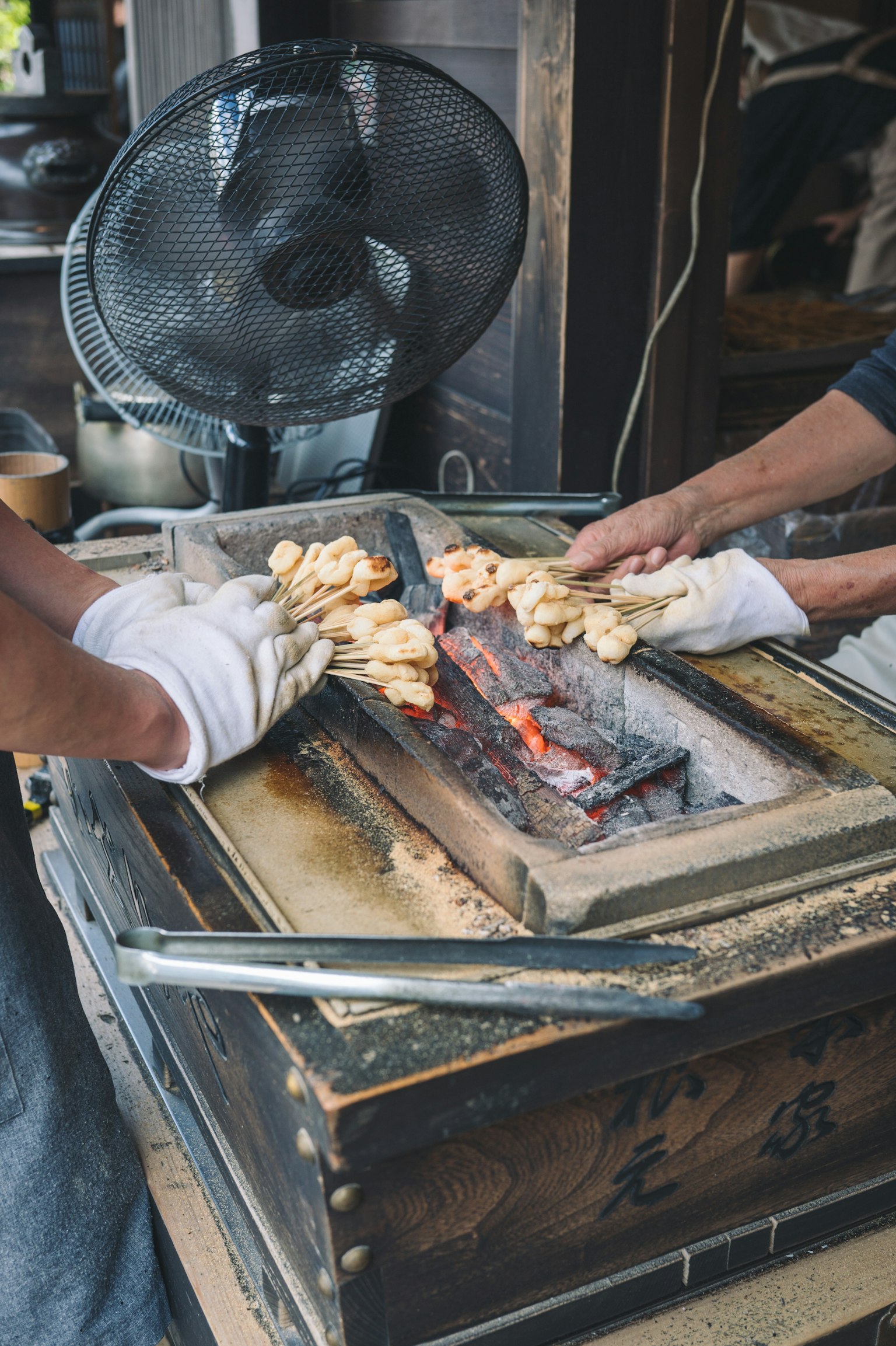 Dua tangan menangani makanan yang dipanggang di atas arang