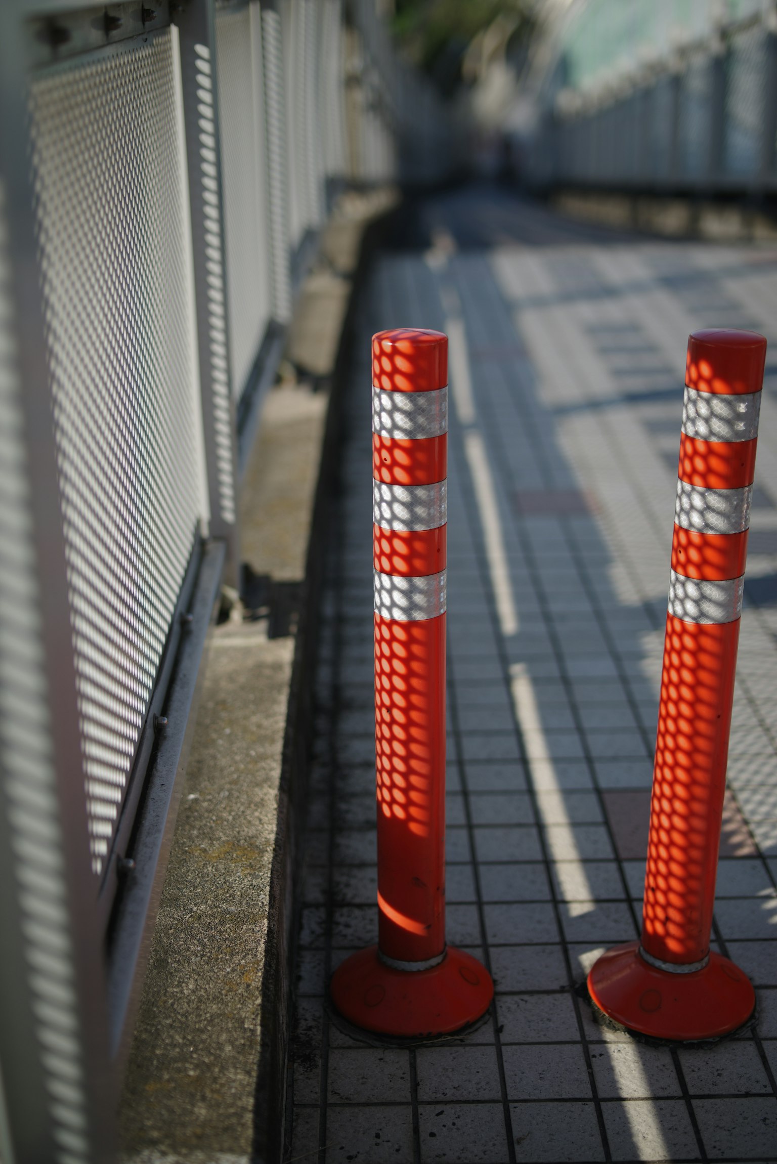 Zwei rote Verkehrskegel auf einem gefliesten Gehweg platziert