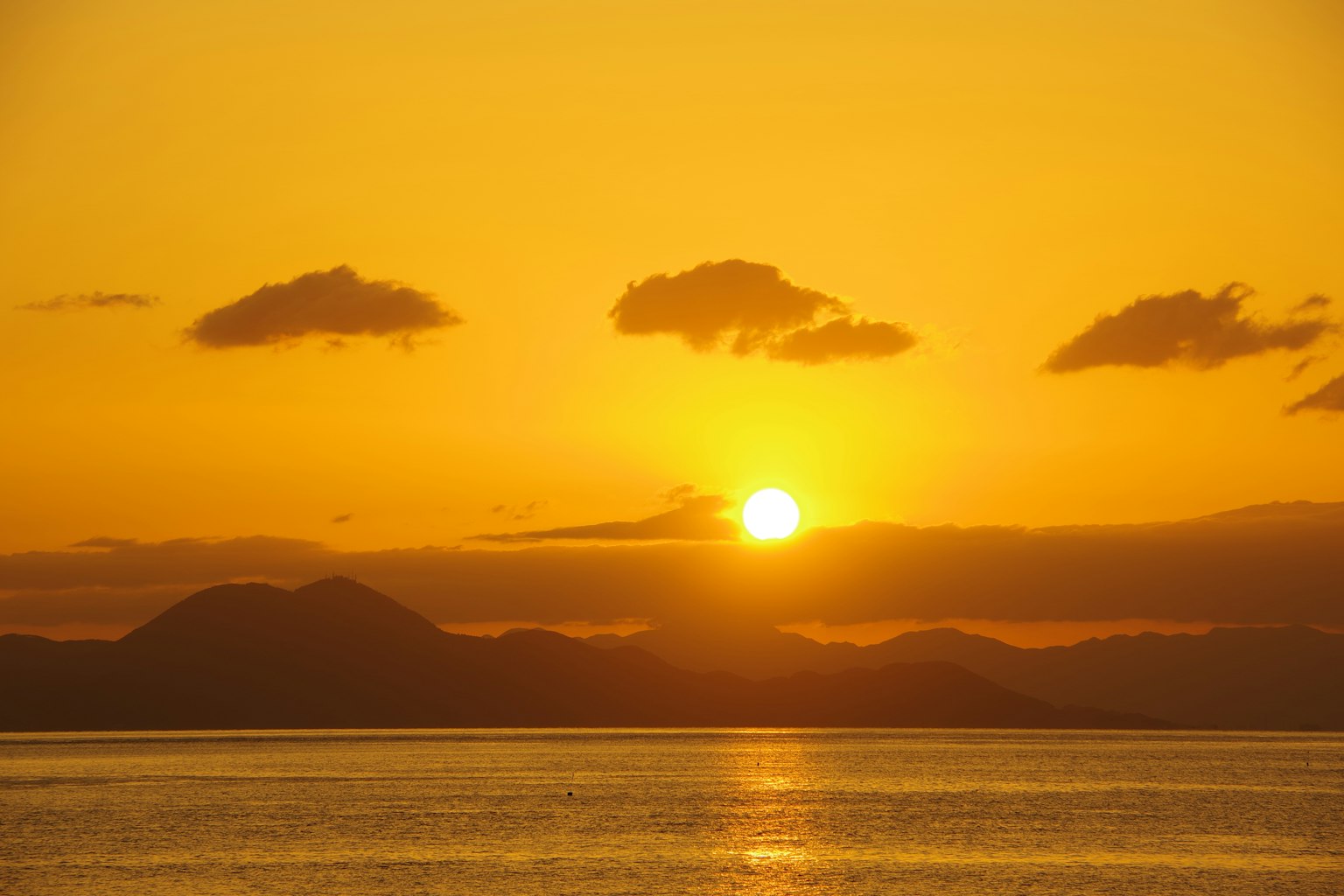 Coucher de soleil magnifique sur l'océan avec des montagnes en silhouette