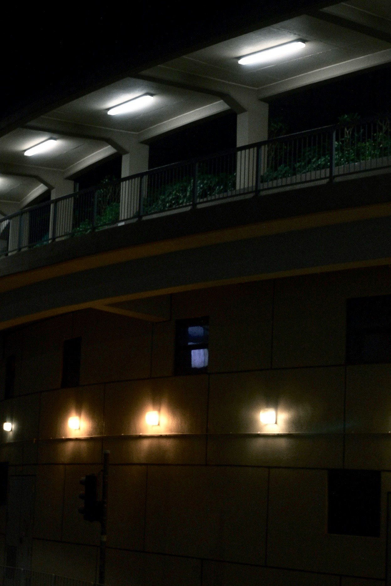 lorong dalam ruangan malam hari dengan deretan lampu dan pagar balkon