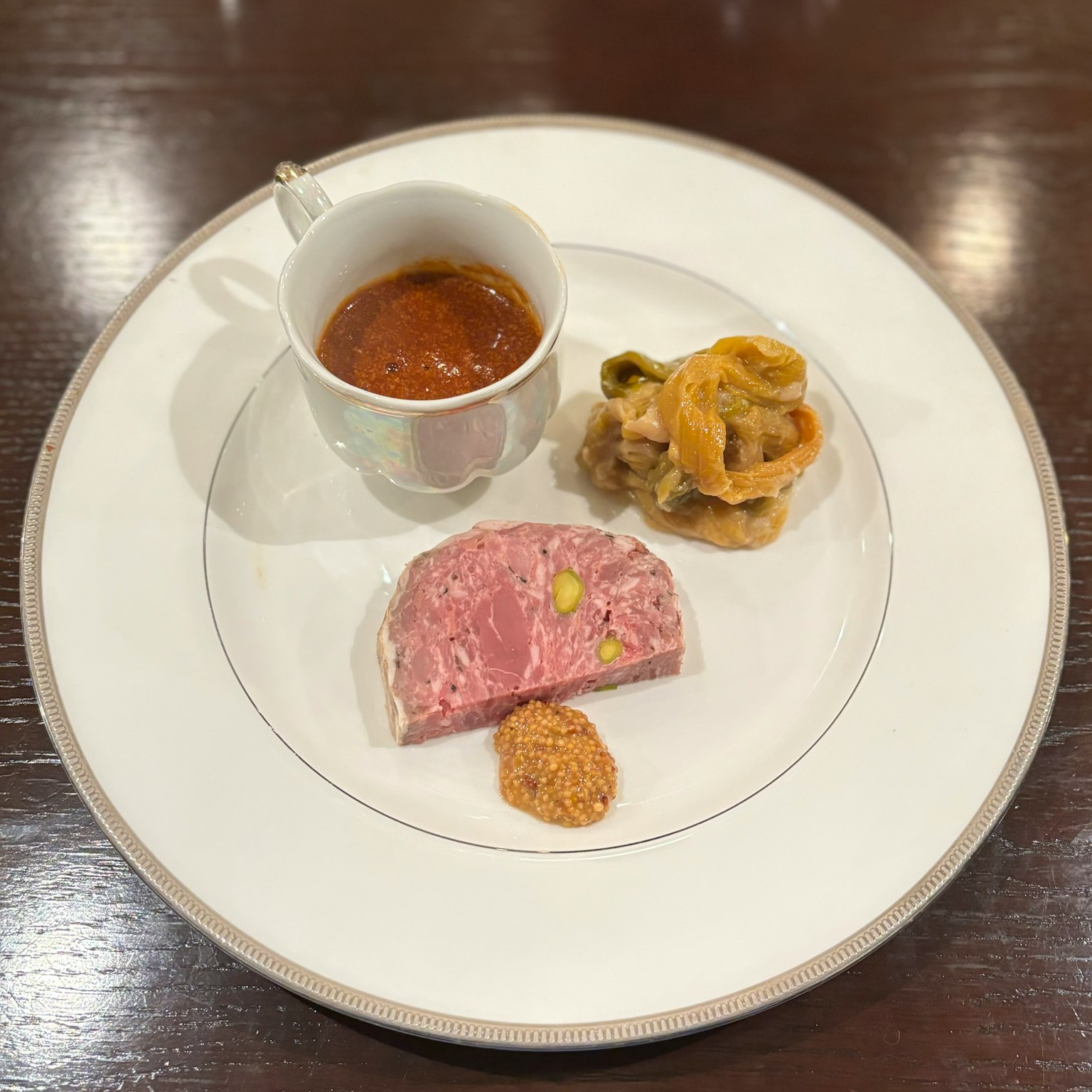 Un piatto bianco con un piatto di carne accompagnato da una piccola tazza di salsa