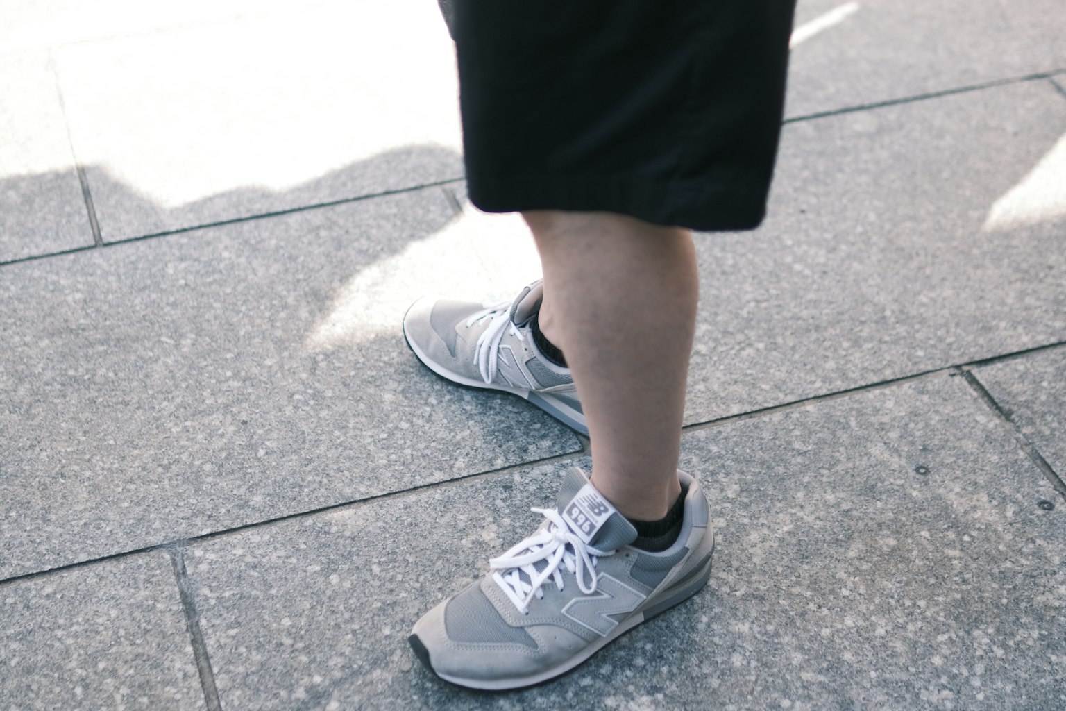Cận cảnh đôi chân mang giày thể thao xám và quần short đen