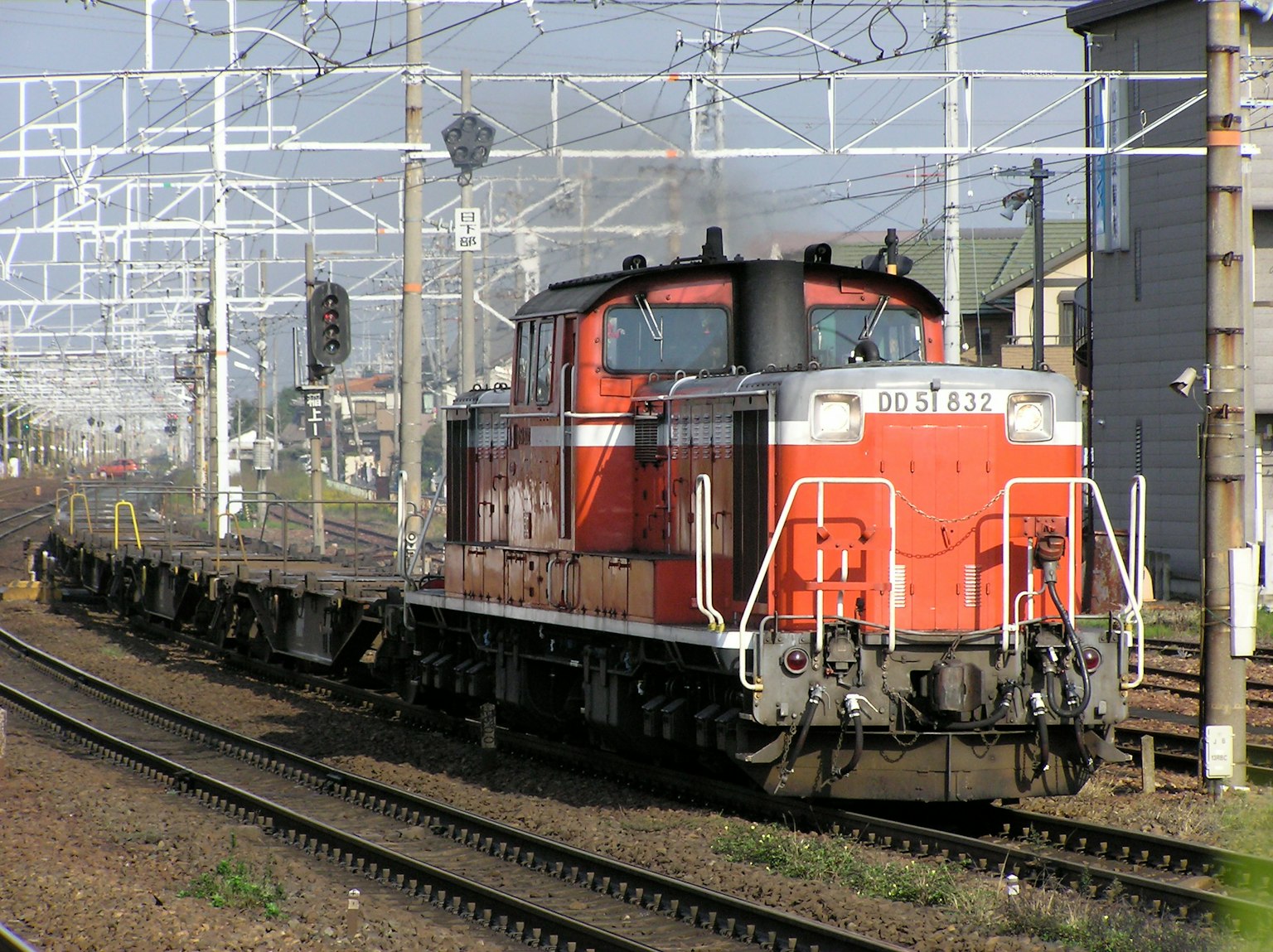 赤いディーゼル機関車が貨物列車を牽引している風景