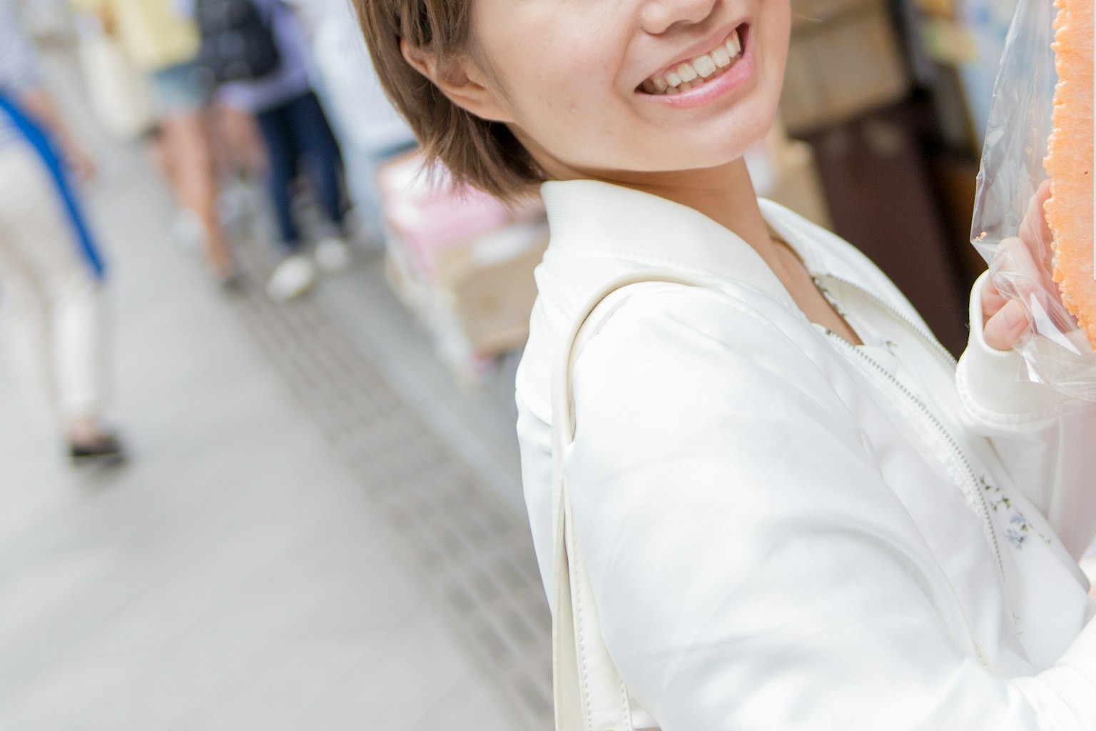 ผู้หญิงยิ้มในแจ็คเก็ตเบาสบายกำลังสนุกสนานอยู่บนถนน