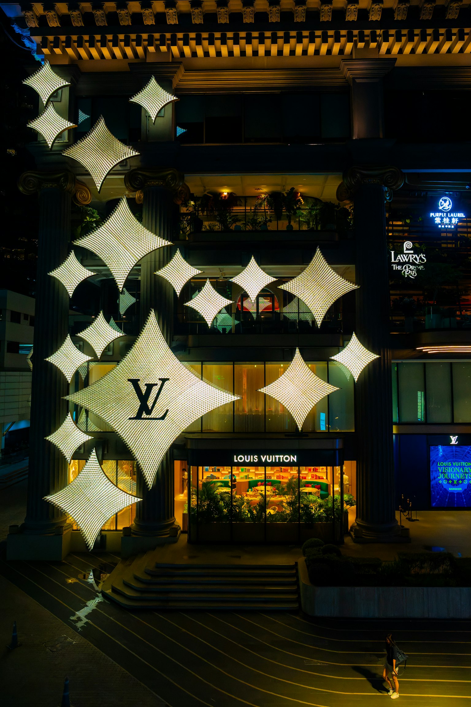 โลโก้ Louis Vuitton ส่องสว่างบนหน้าร้านในตอนกลางคืนพร้อมไฟตกแต่งรูปดาว