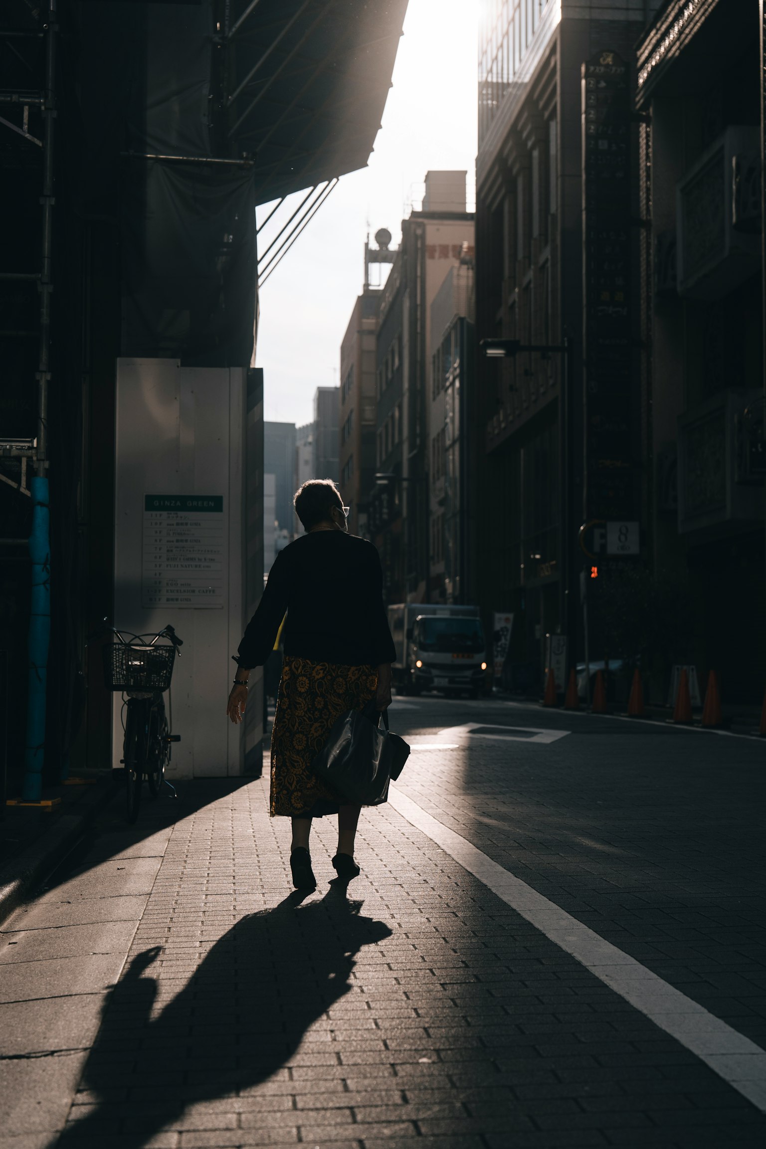 Silhouette einer Frau, die auf der Straße mit städtischen Gebäuden geht