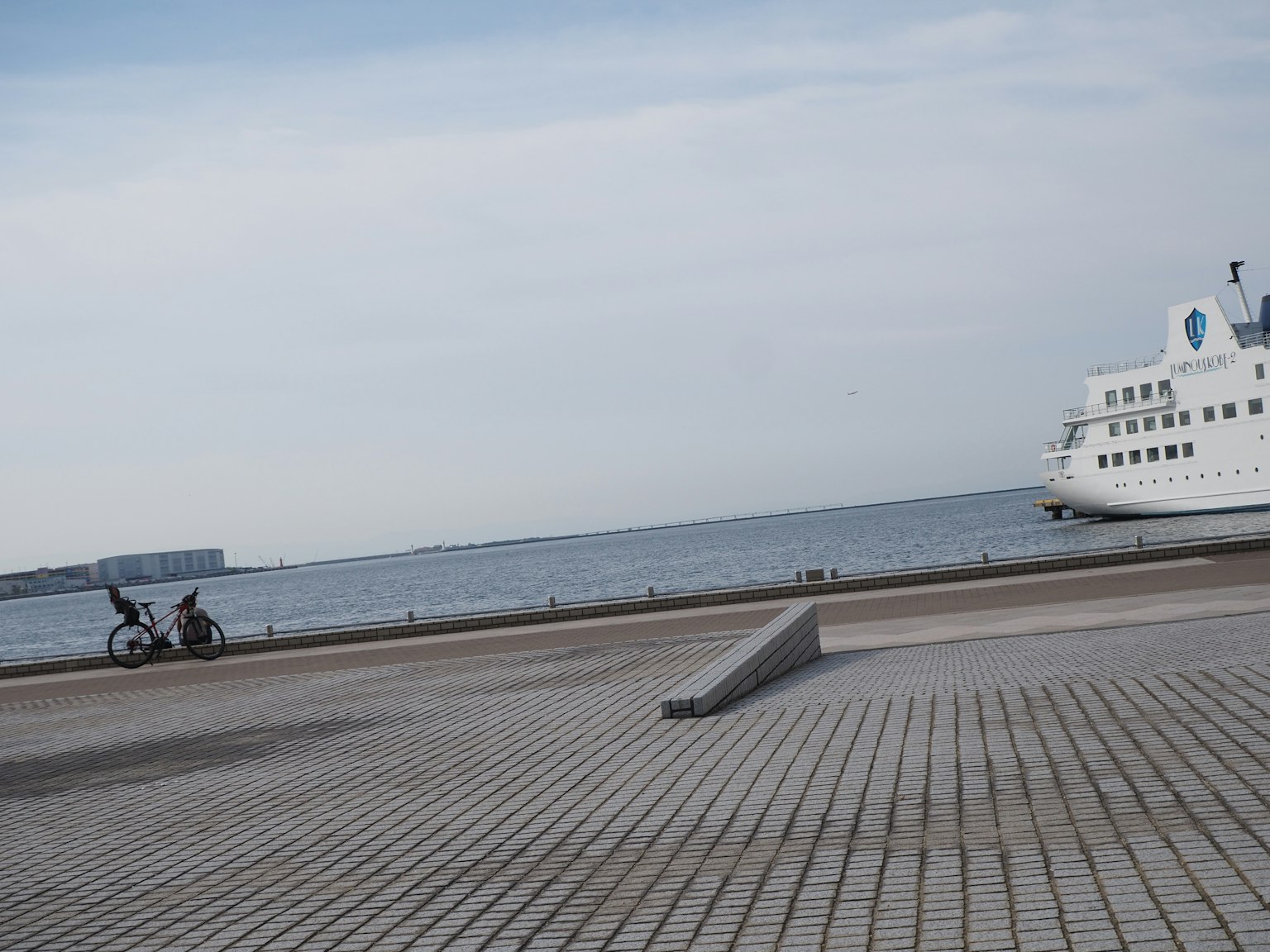 Paisaje costero con un barco atracado y una acera pavimentada