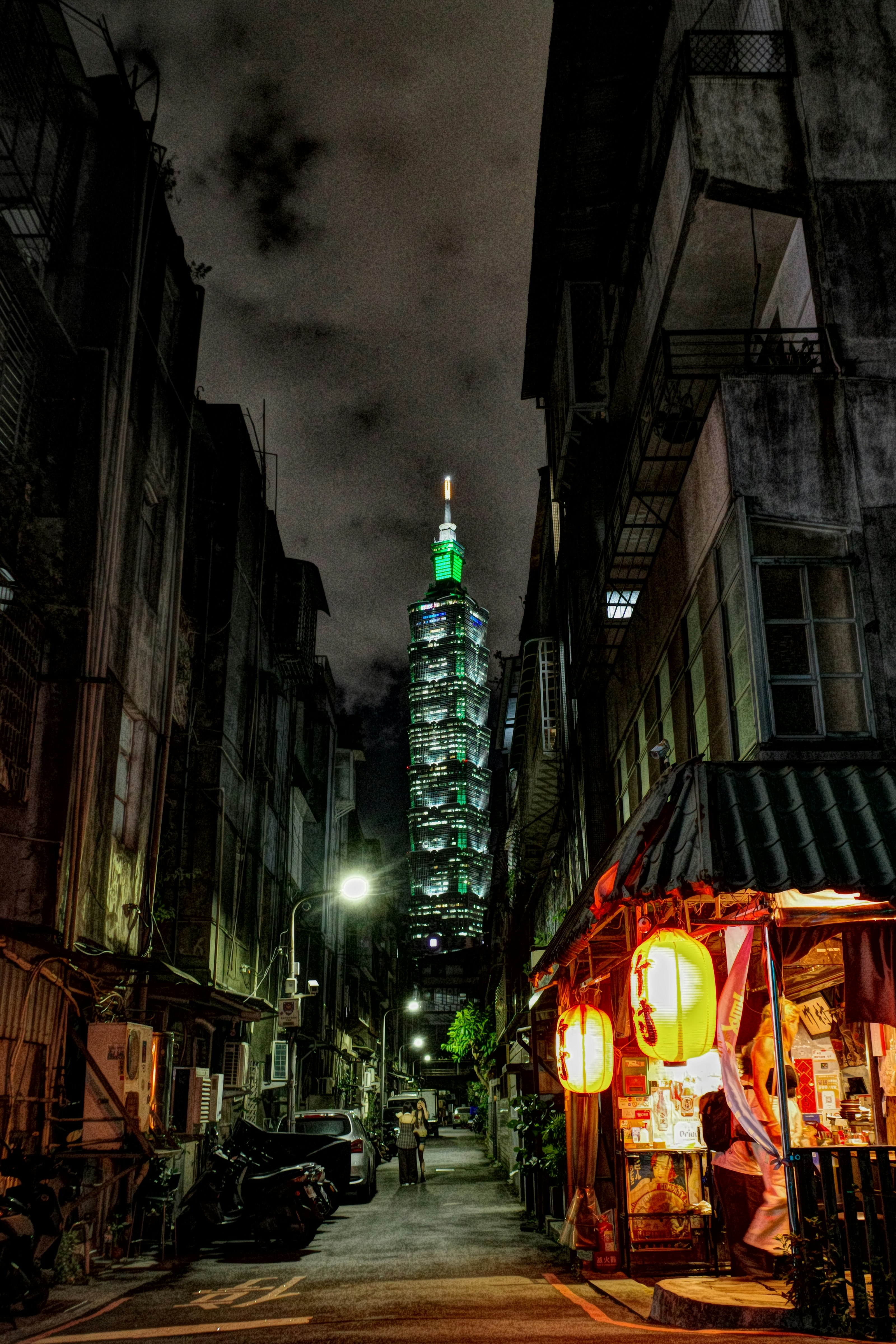 台北の路地に並ぶ屋台と高層ビルの夜景