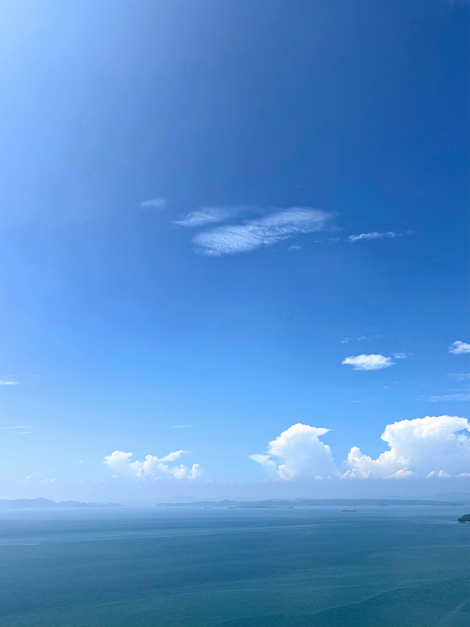 广阔的蓝天和白云覆盖在宁静的海面上
