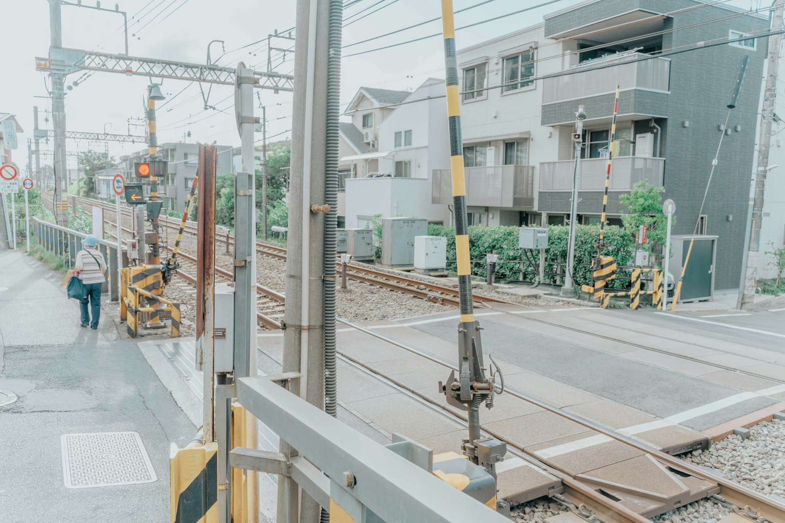 Pemandangan rel kereta dengan seseorang yang berjalan di dekat stasiun