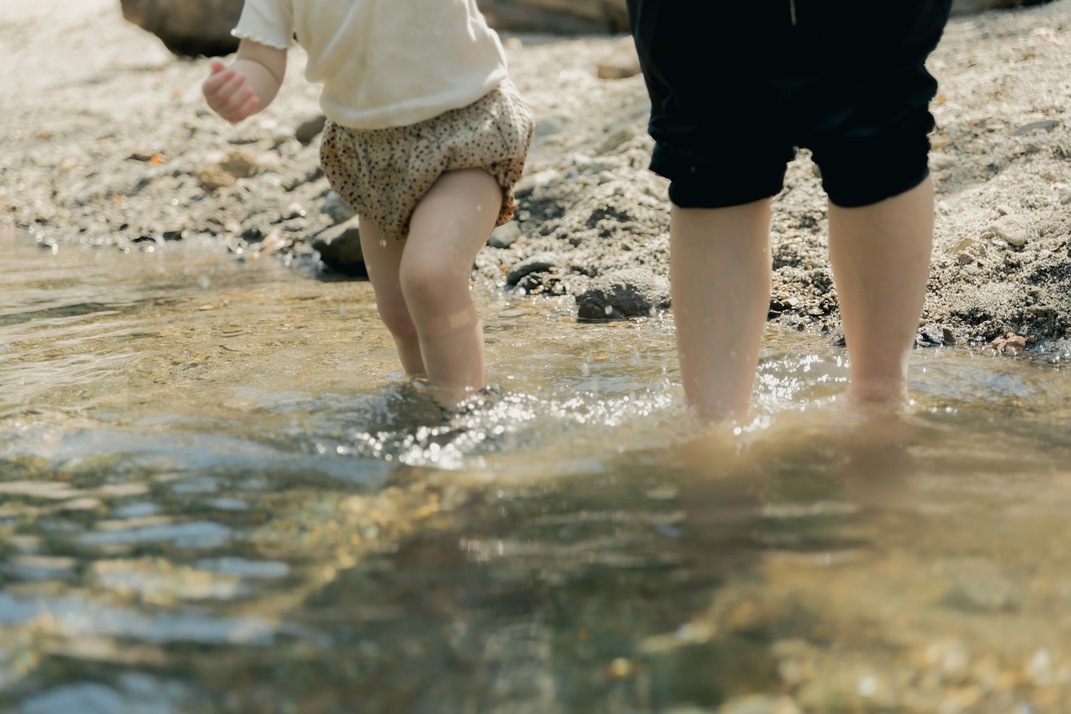 A child and an adult walking in shallow water