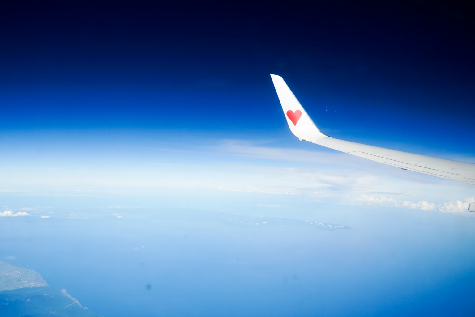 飞机机翼与蓝色天空和海洋的背景