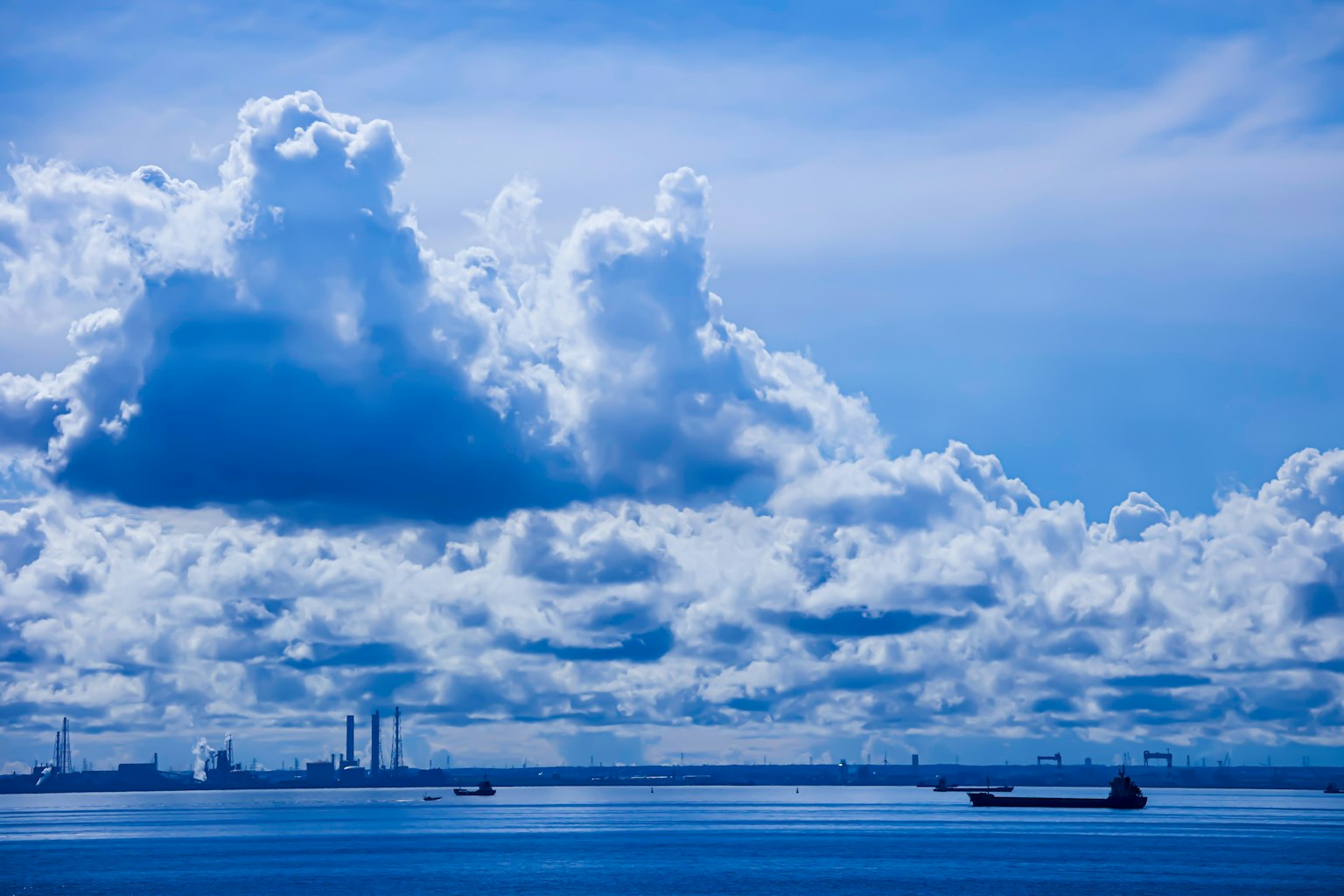 Paysage maritime avec ciel bleu et nuages présentant des navires sur l'eau