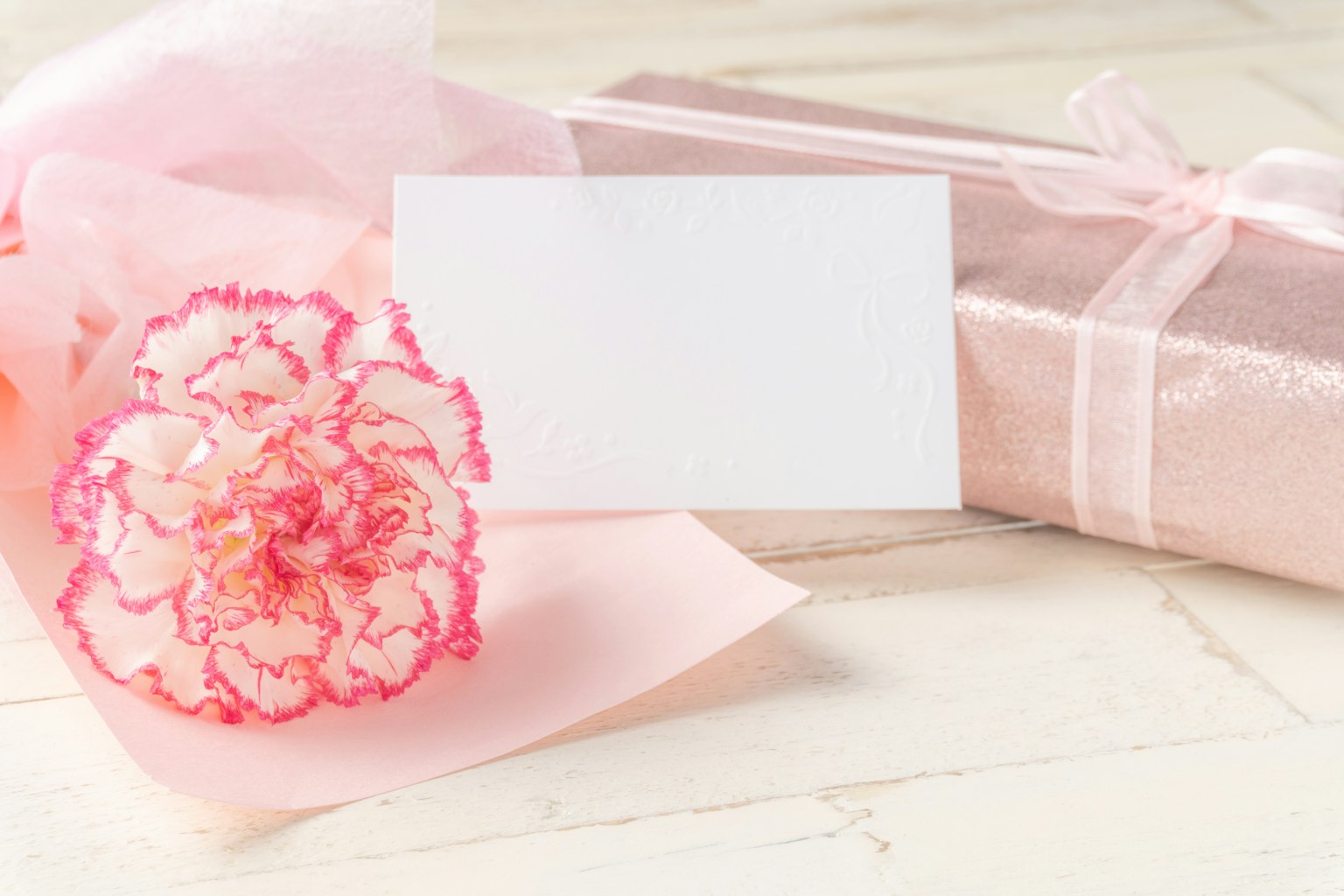 Una scena con un fiore rosa chiaro e un regalo incartato