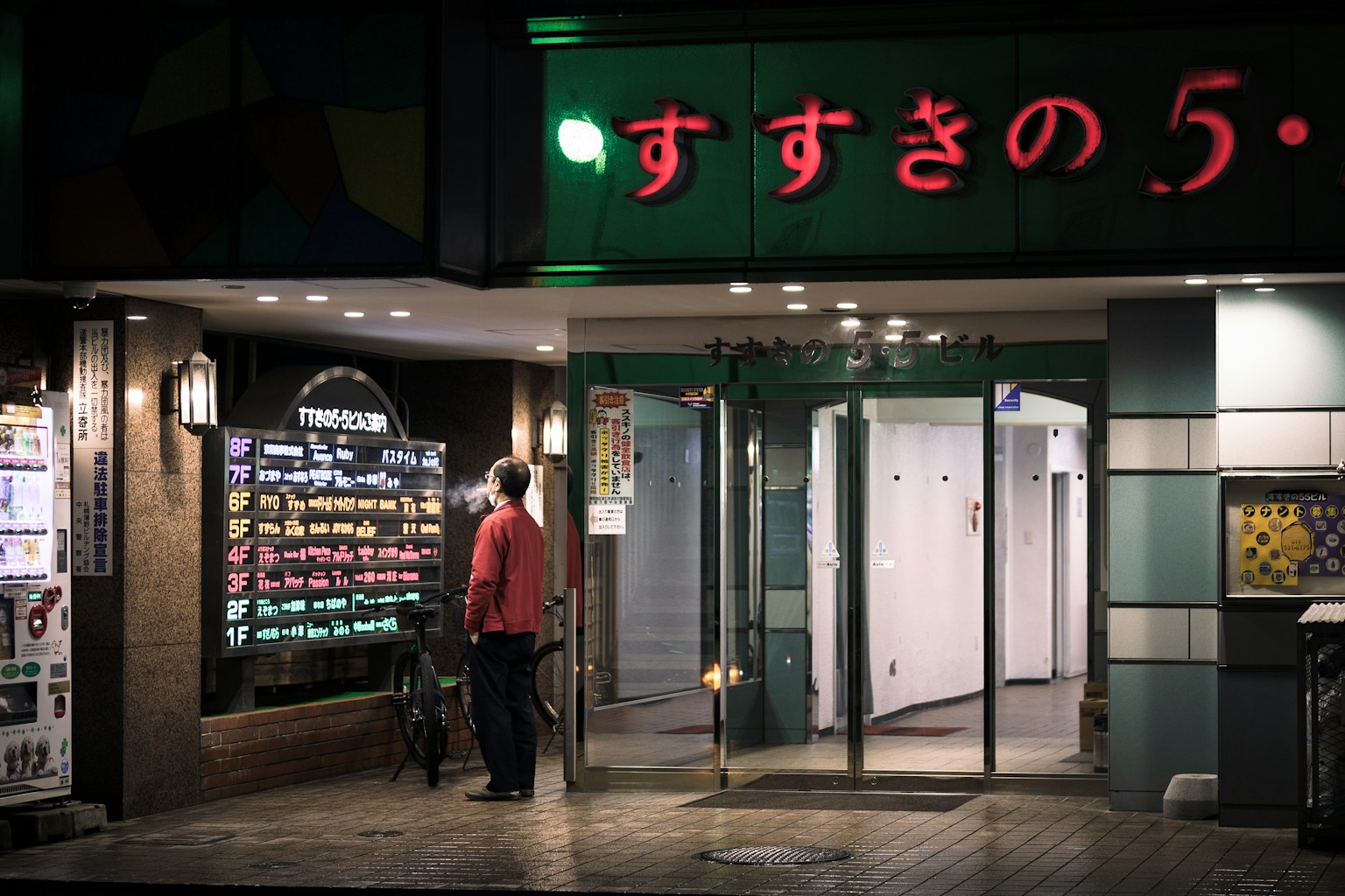 Exterior of a Japanese restaurant with red neon sign a man looking at the menu