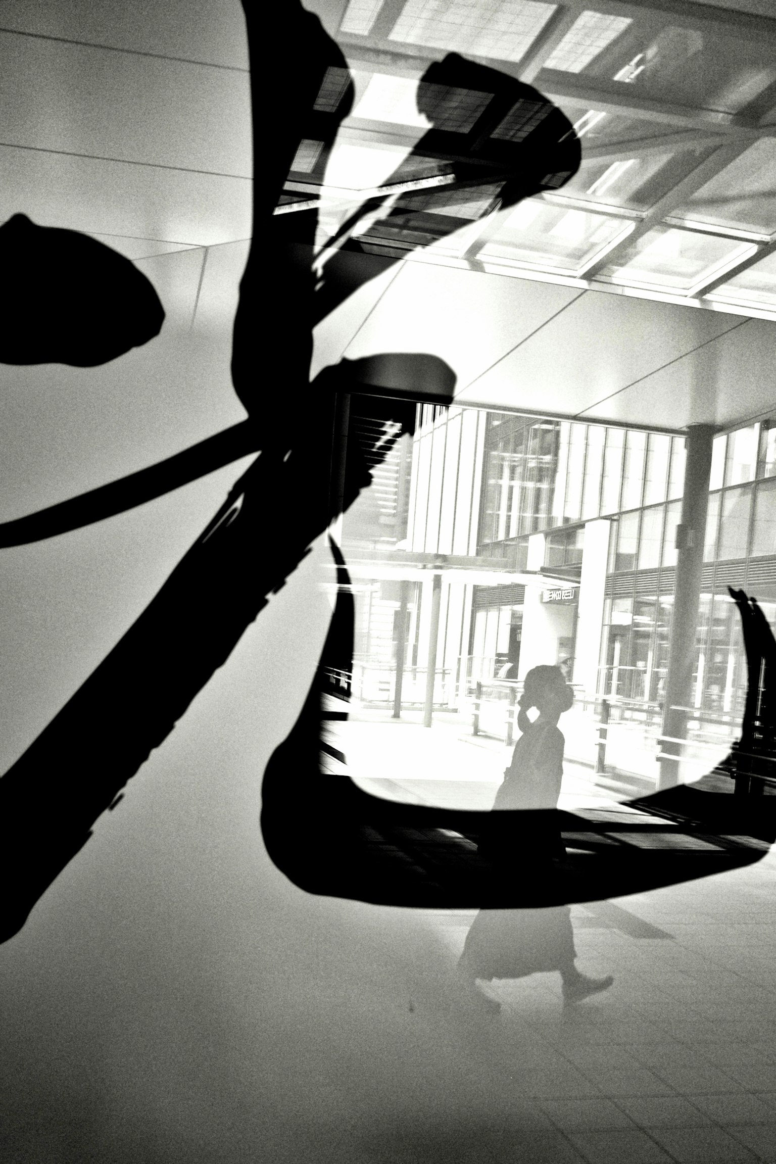 Silhouette di una persona che cammina dietro un vetro con calligrafia nera