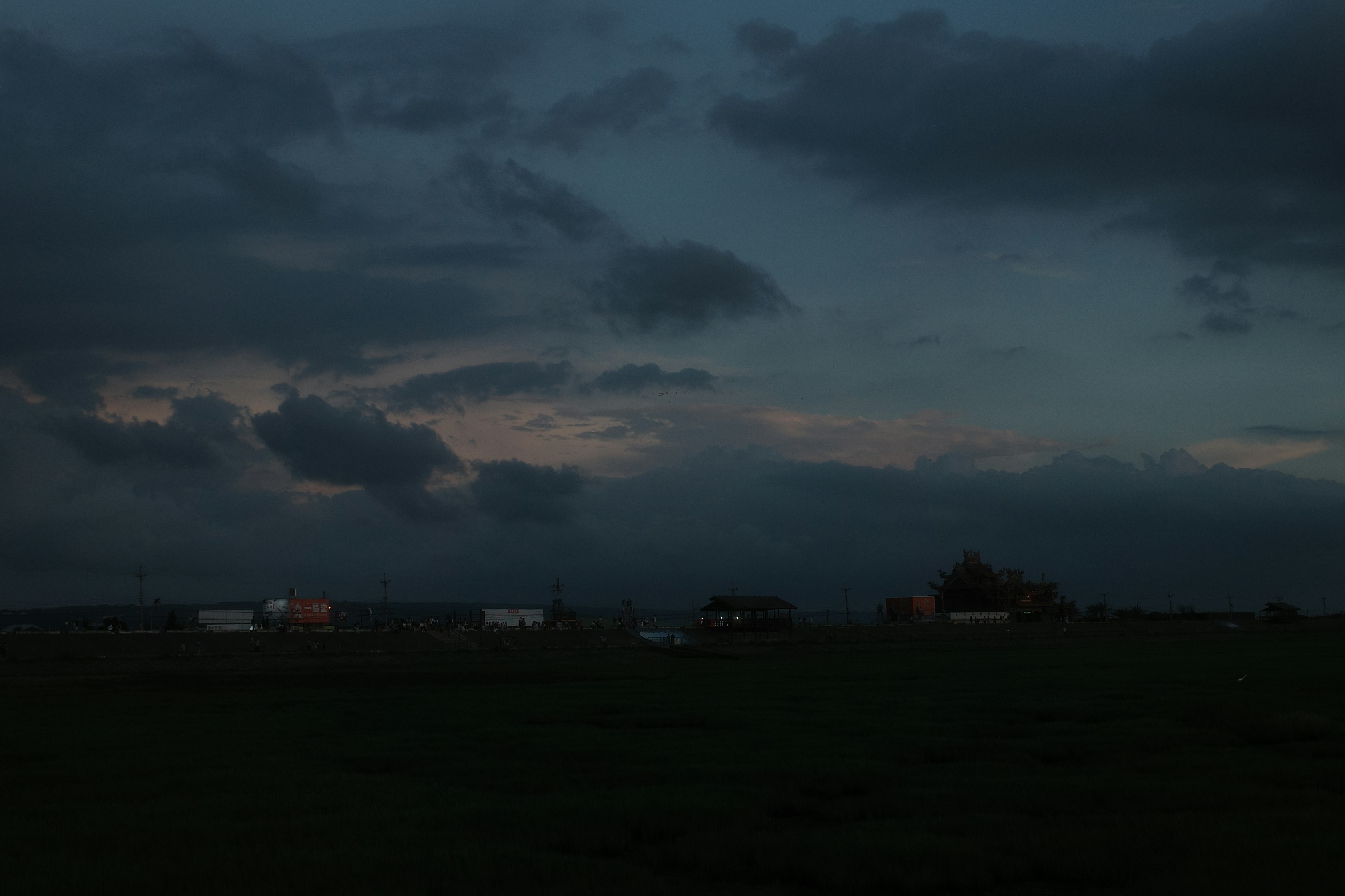 夕暮れの広い草地に流れる車と雲の空