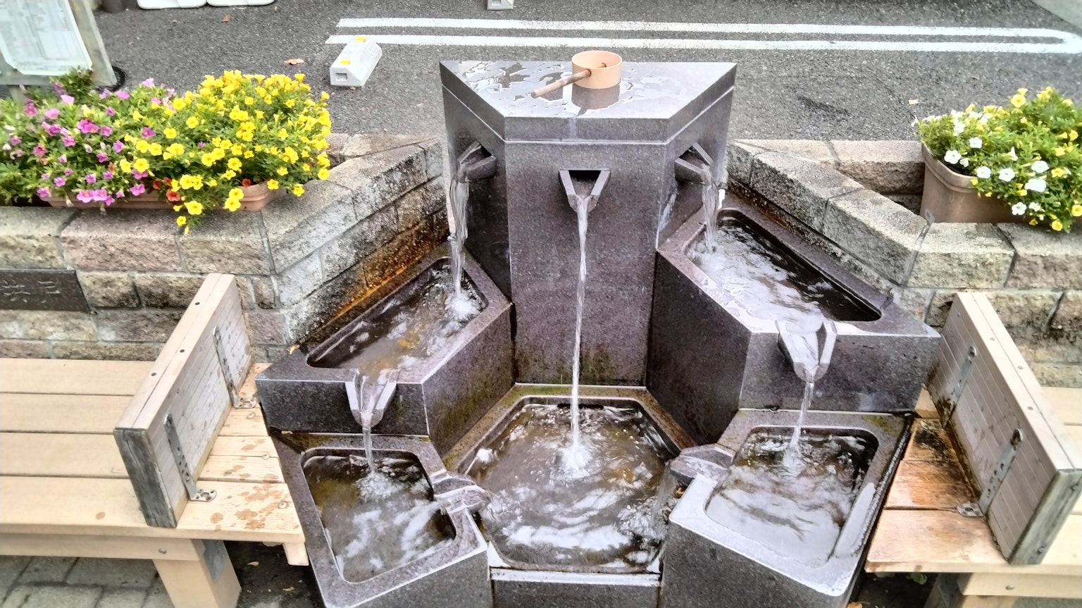 Fontana moderna con acqua che scorre circondata da fiori in fiore