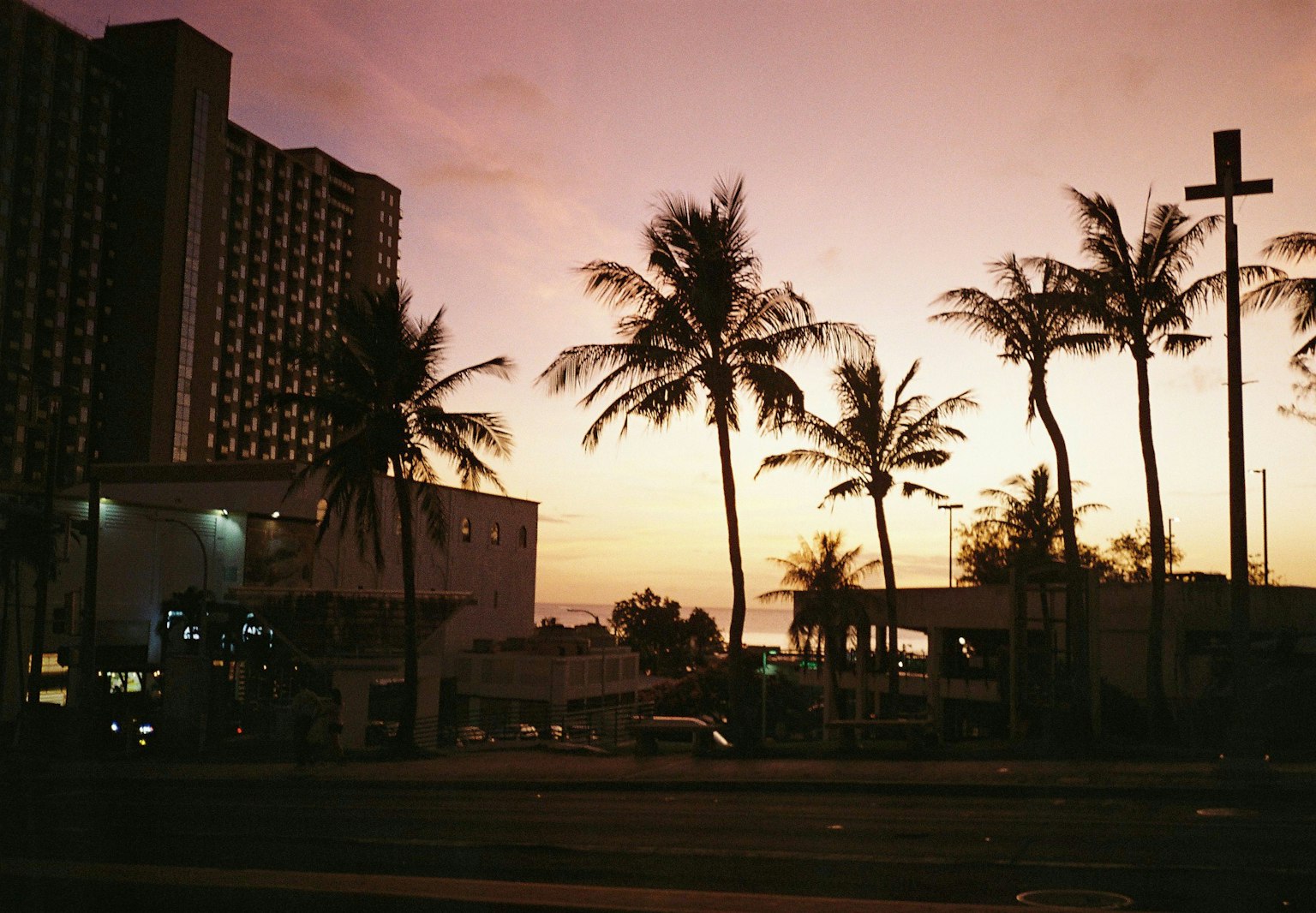 Silueta de palmeras y hotel contra un cielo al atardecer