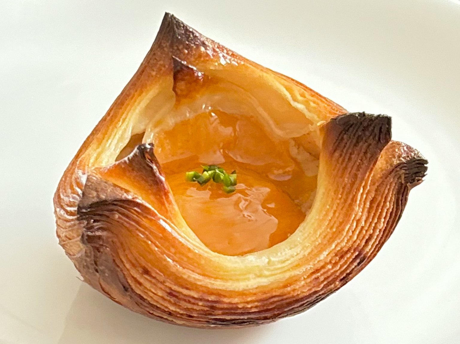 Una pasticceria caramellata con un centro lucido riempito di gelatina trasparente e guarnita con erbe verdi