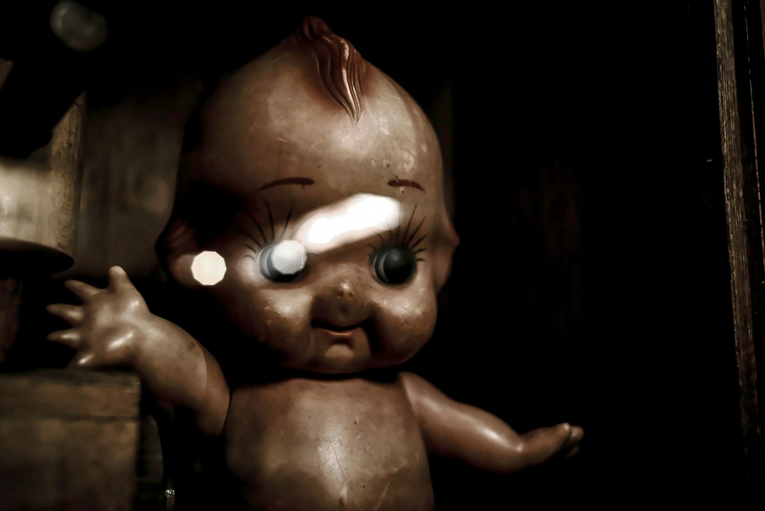 Close-up boneka menyeramkan berdiri di latar belakang gelap