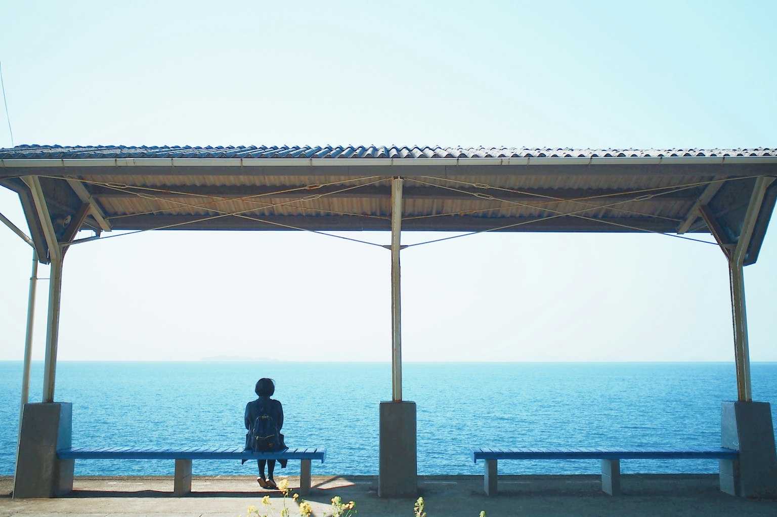 Silueta de una persona mirando al mar bajo un pabellón